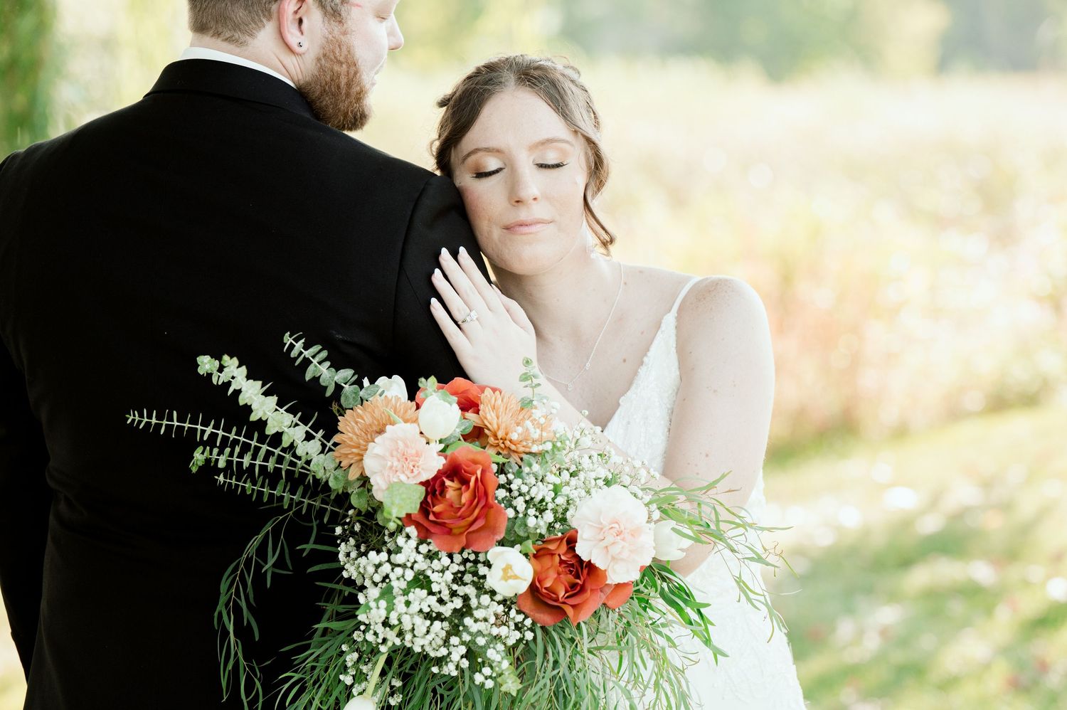 The Grands At Mulligans outdoor wedding photoshoot featuring a bride and groom embracing amid natural greenery and floral arrangements.