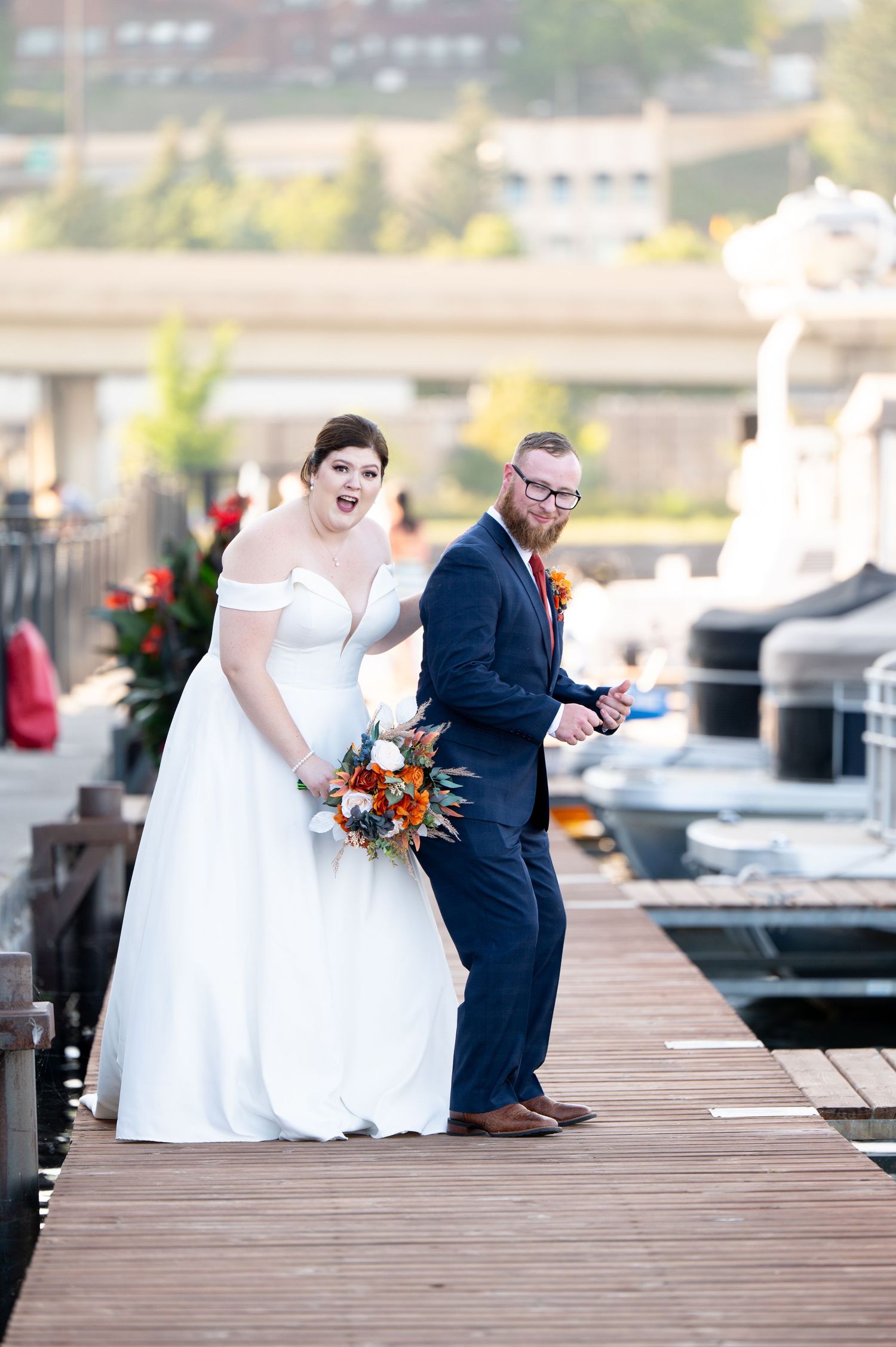 Pier B Duluth Wedding Wedding couple shares candid moments while walking along wooden pier by waterfront setting.