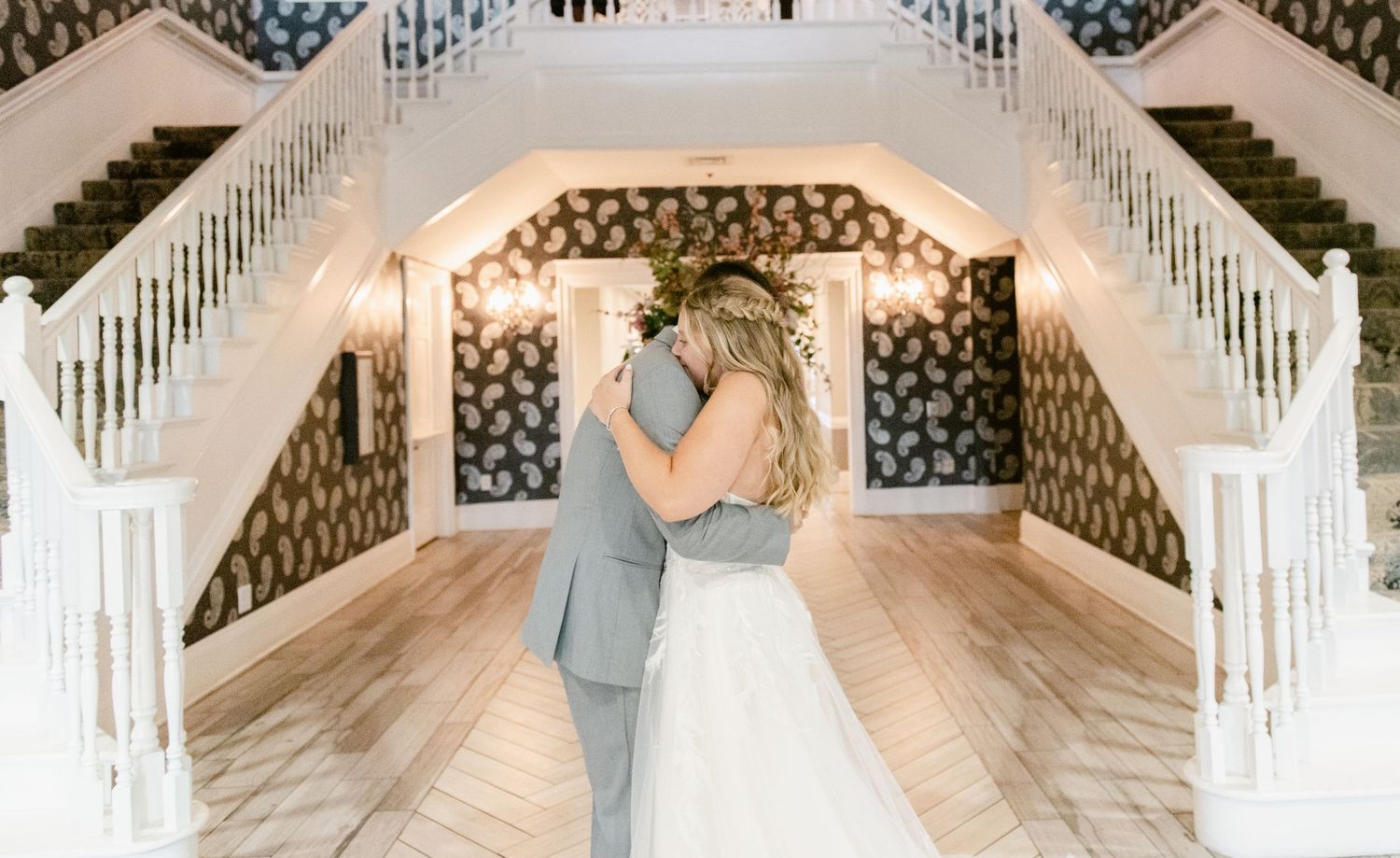 Romantic moment between newlyweds under arched staircase with decorative lighting.