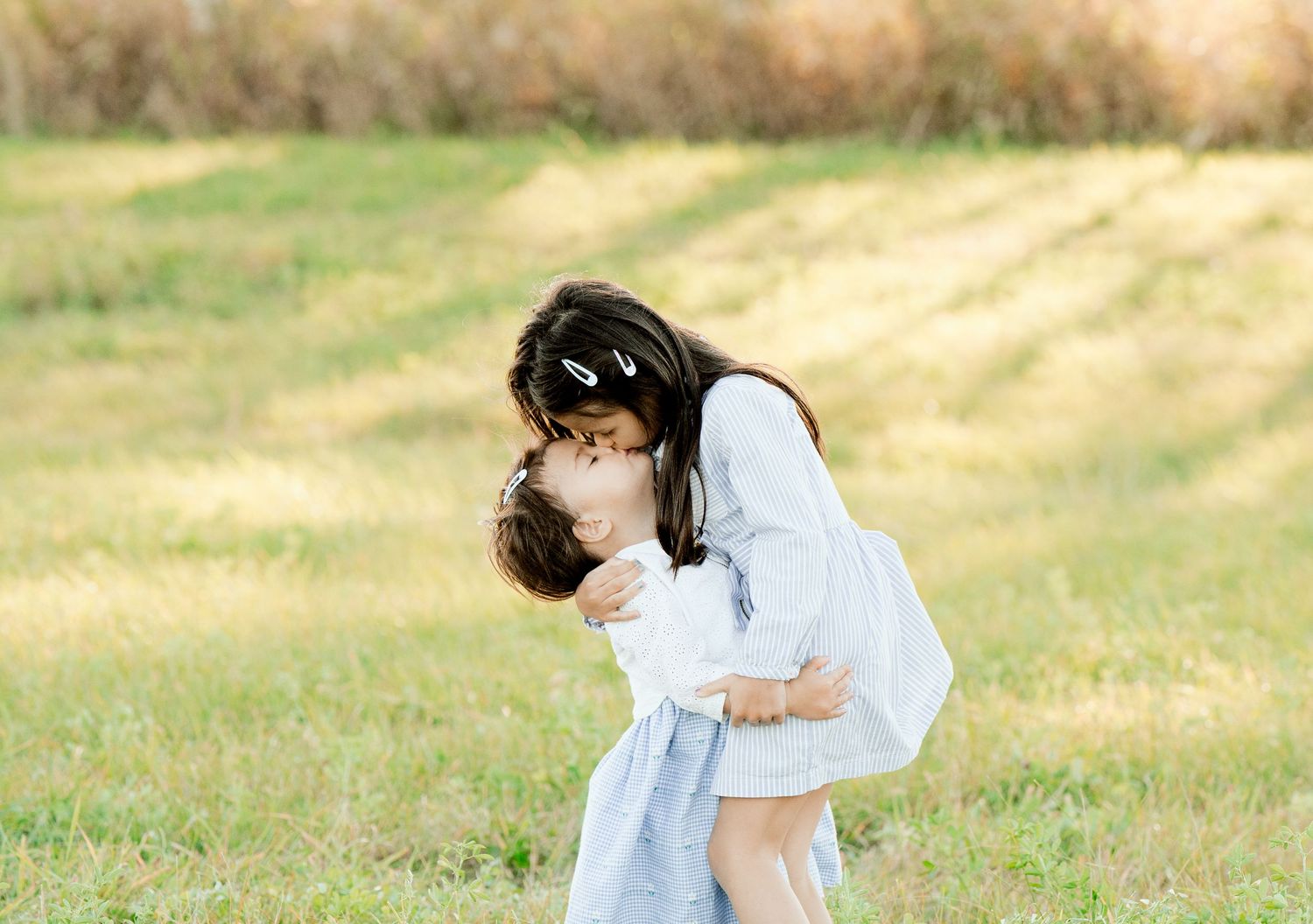 Parent and child sharing tender moment outdoors in golden sunlight.