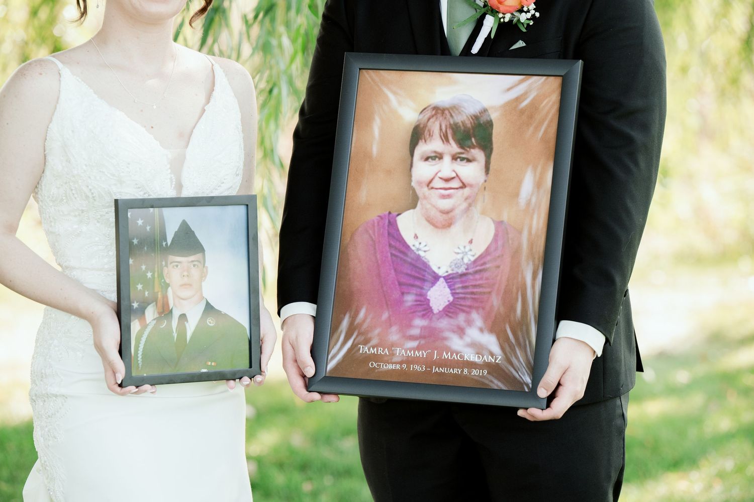 Wedding party members hold framed photos in an outdoor garden setting.