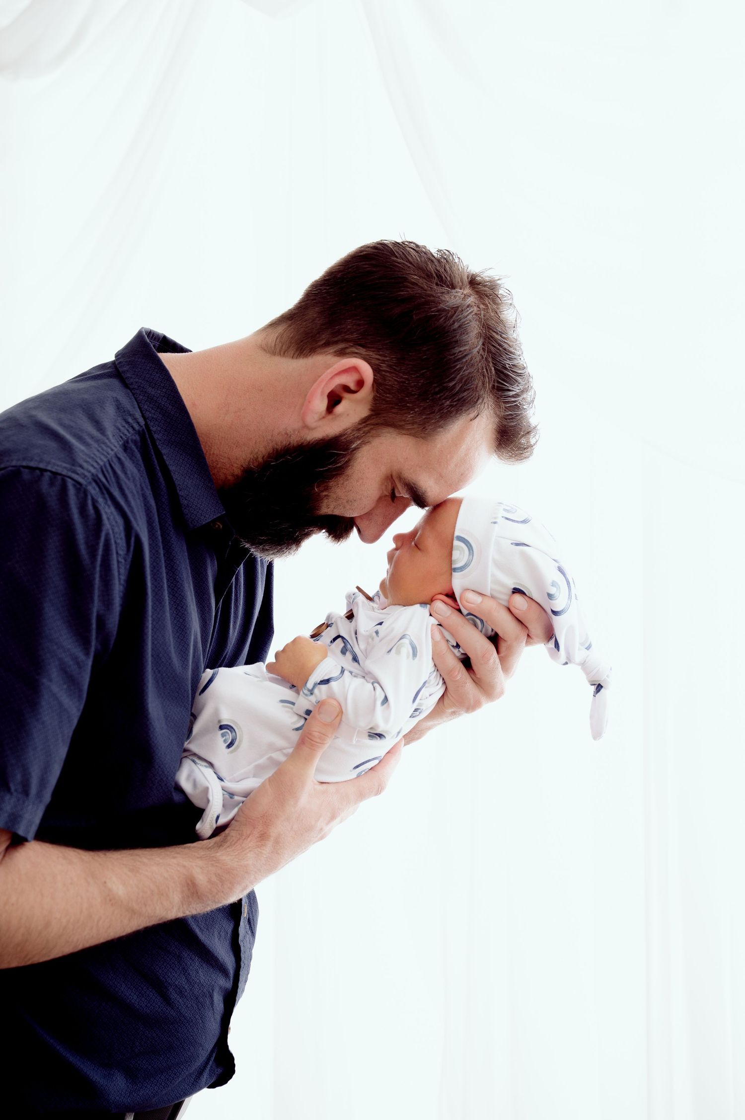 An intimate moment between parent and newborn in a bright, minimalist setting.