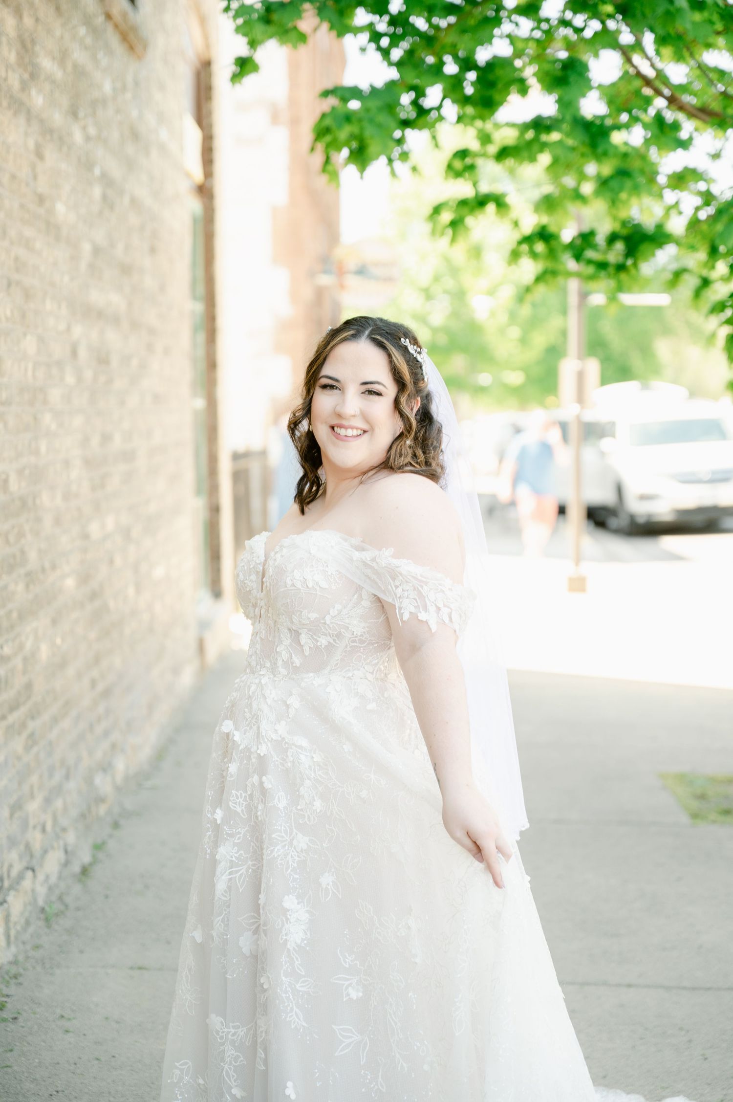 Bride walking along building exterior with natural greenery overhead.