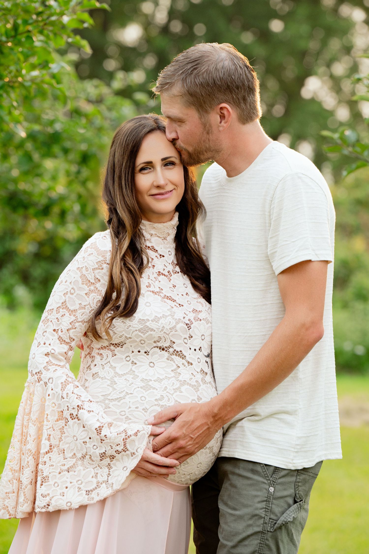 An intimate portrait of a couple during their maternity photoshoot in a lush garden.