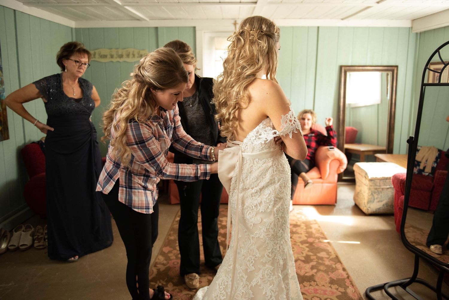 Final wedding dress adjustments being made in a mint-colored preparation room.