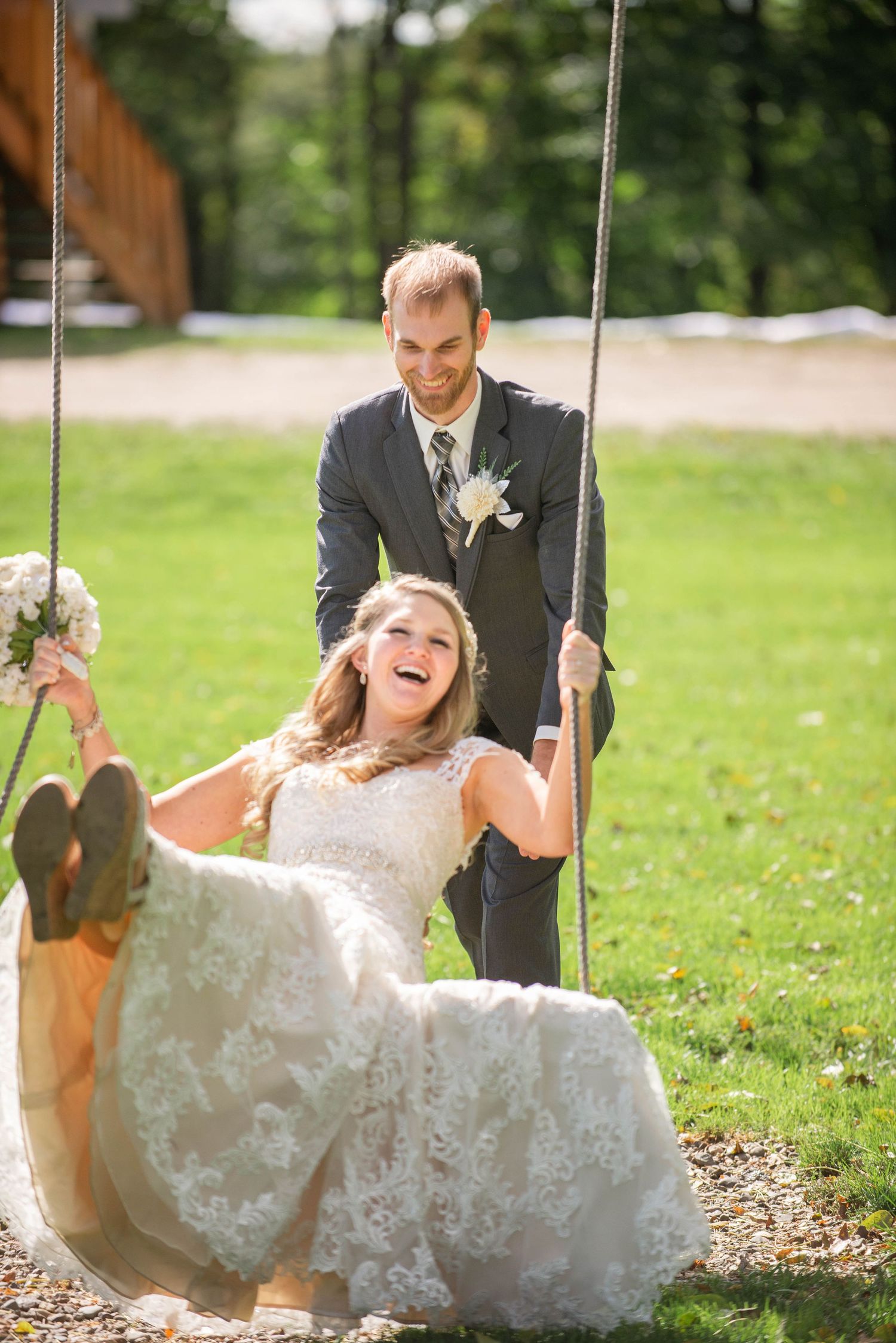 A joyful wedding moment captured on a swing in a sunny garden setting. Rum River Barn Milaca Minnesota Weddings
