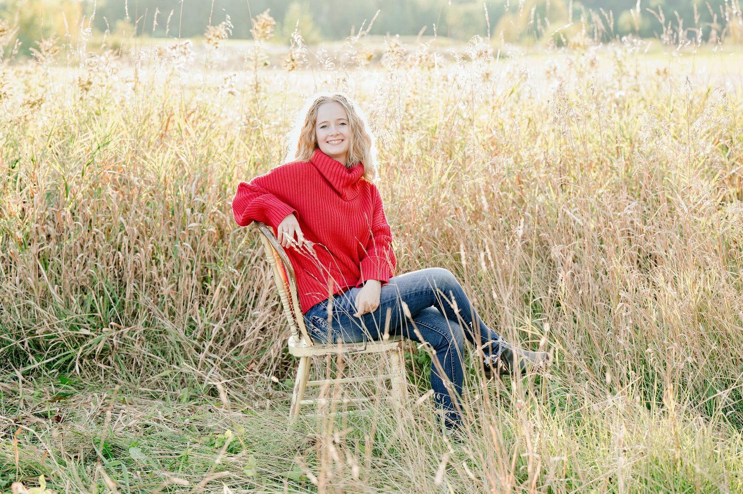 Senior Portrait in Foreston MN Person in red jacket sitting among tall autumn grasses during outdoor photography session.