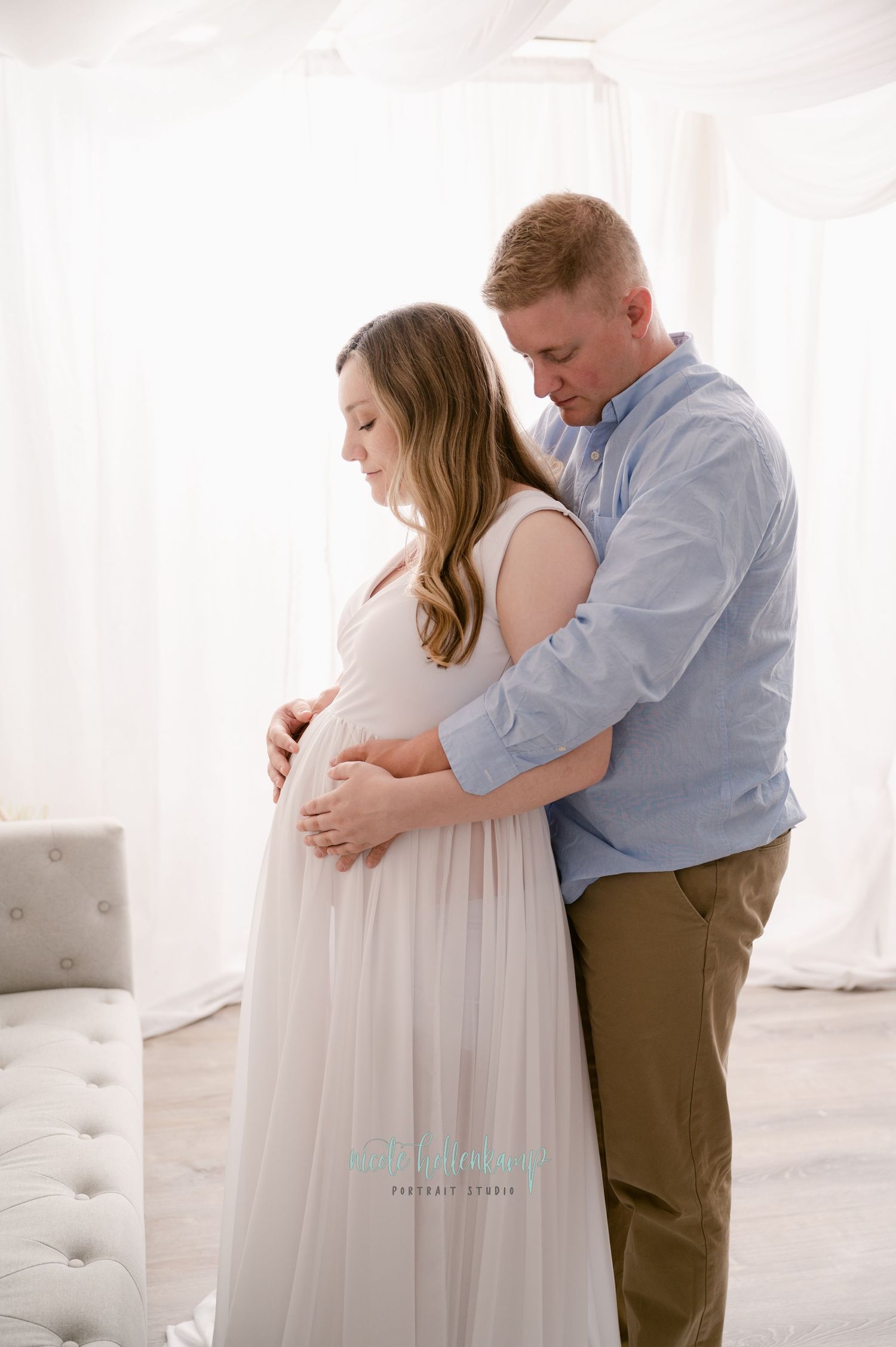 A couple embraces in a light-filled space as they share an intimate moment during a maternity photo shoot.