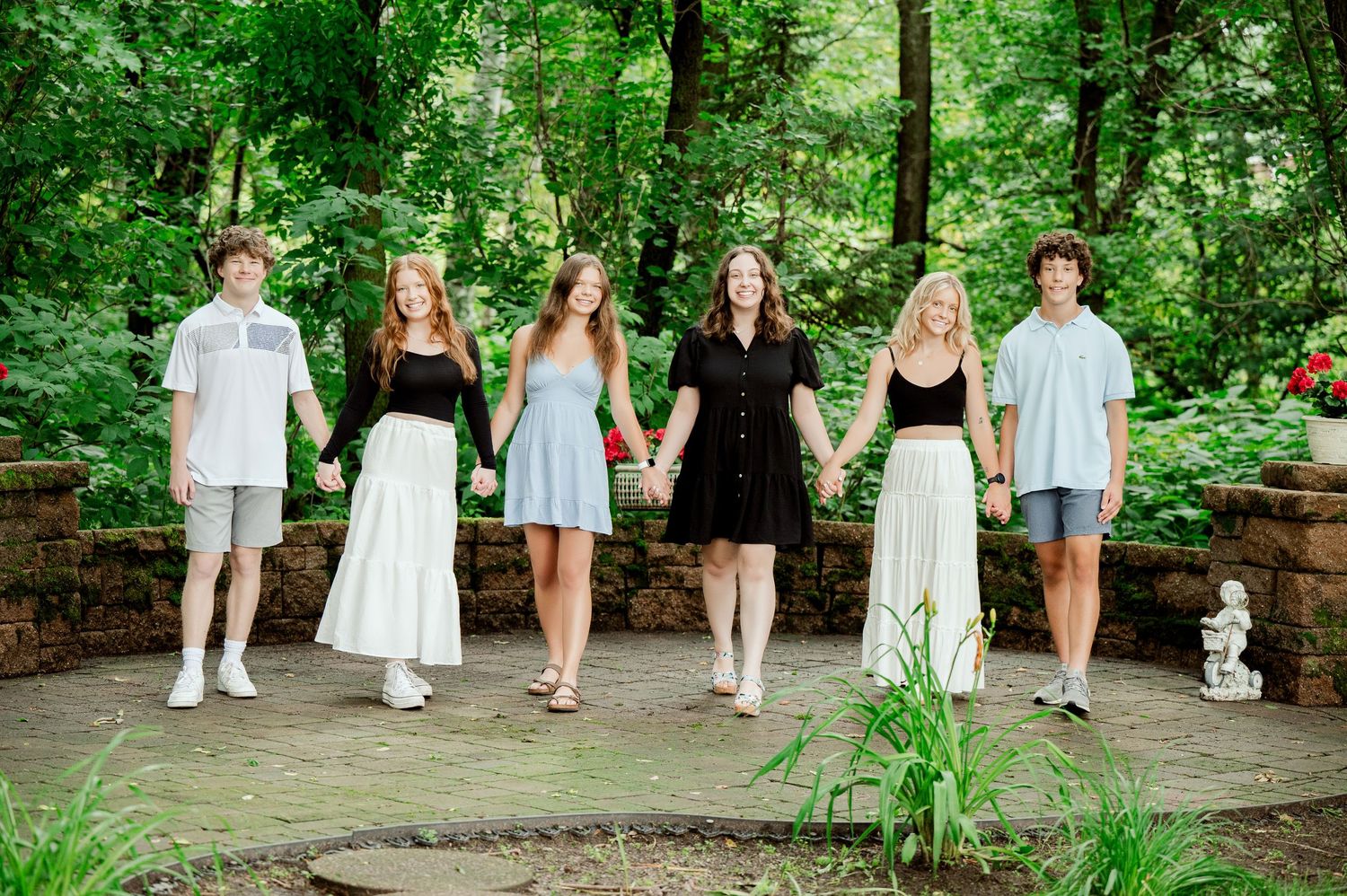 Candid wedding party moment in the woods during summer with a traditional bridal party wearing white dresses.