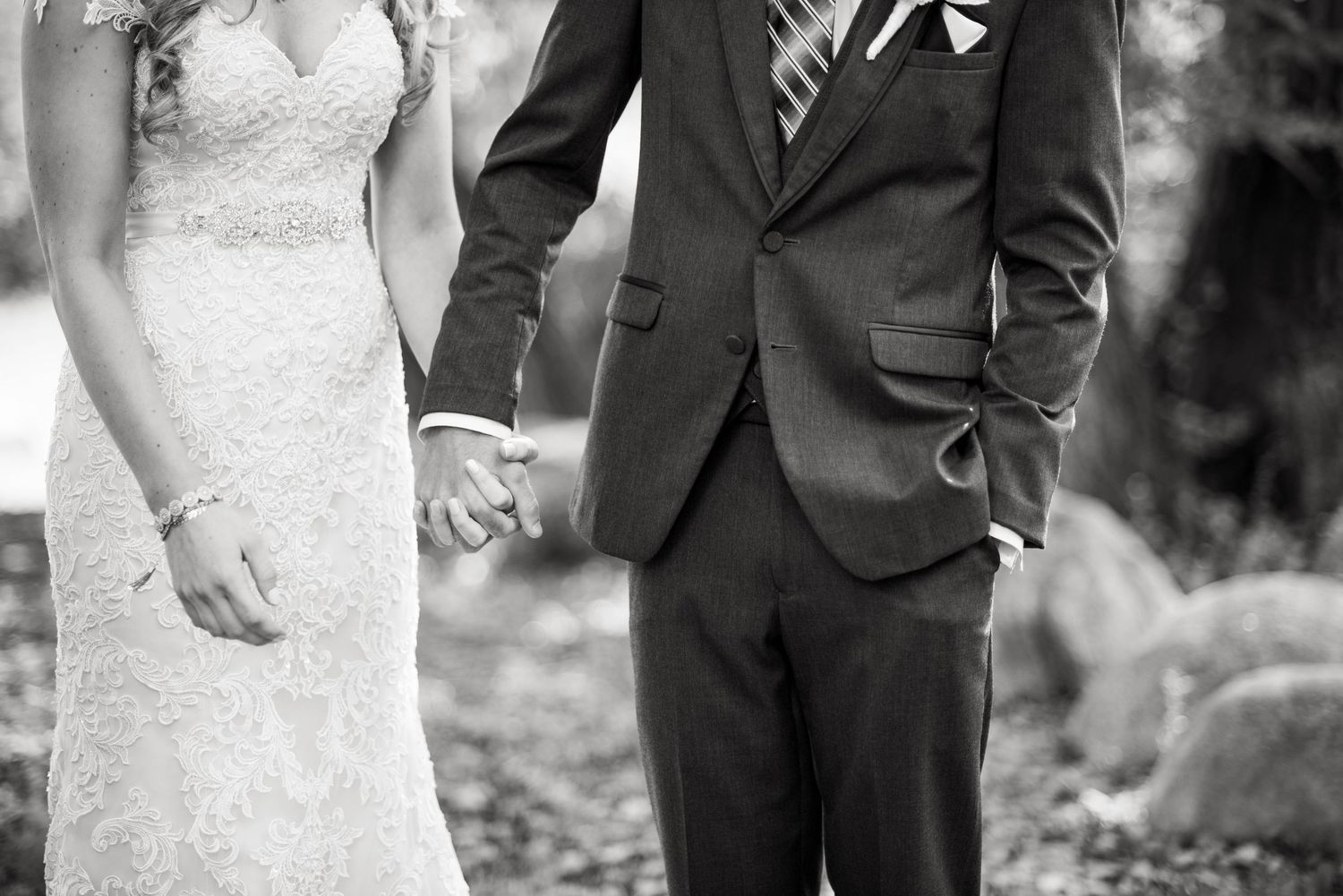 Wedding couple walks through a scenic garden path in formal attire.