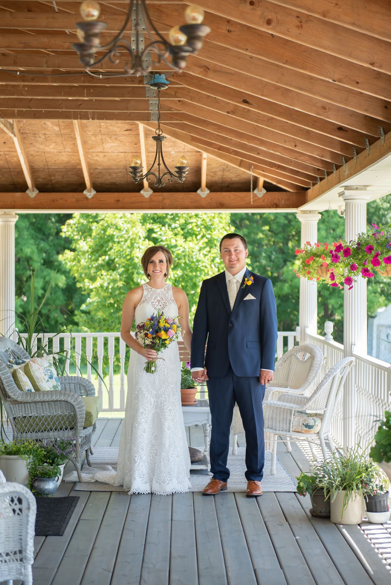 Wedding couple poses progressively along a rustic wooden porch with white columns and hanging flower baskets.