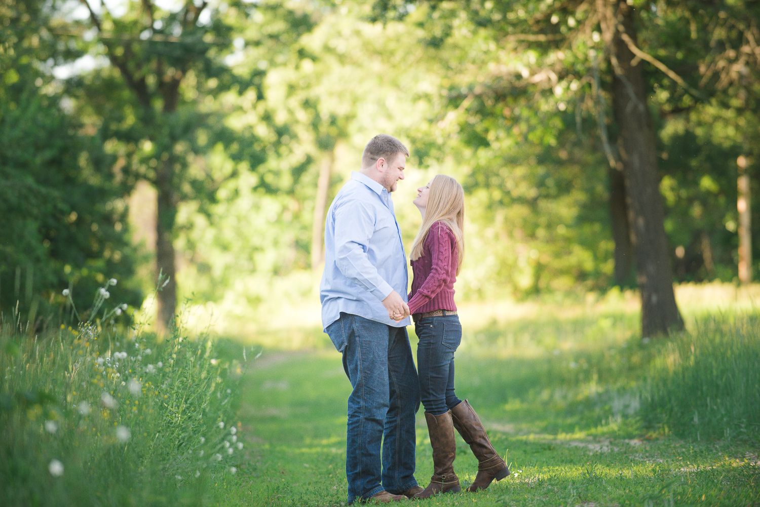 Romantic outdoor photoshoot in a sunlit park with soft natural lighting and trees in the background.
