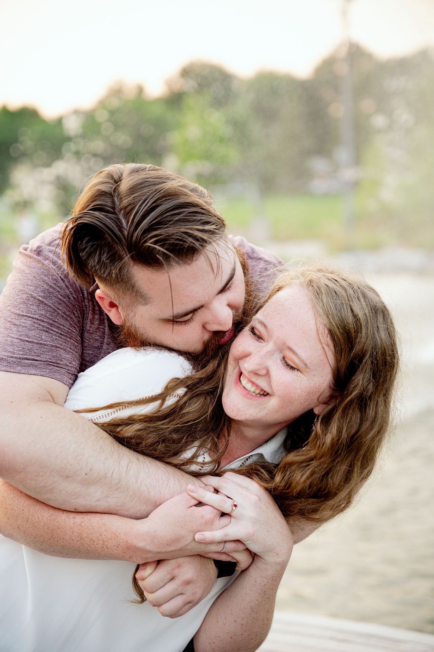 Affectionate couple laughs together while embracing outdoors.