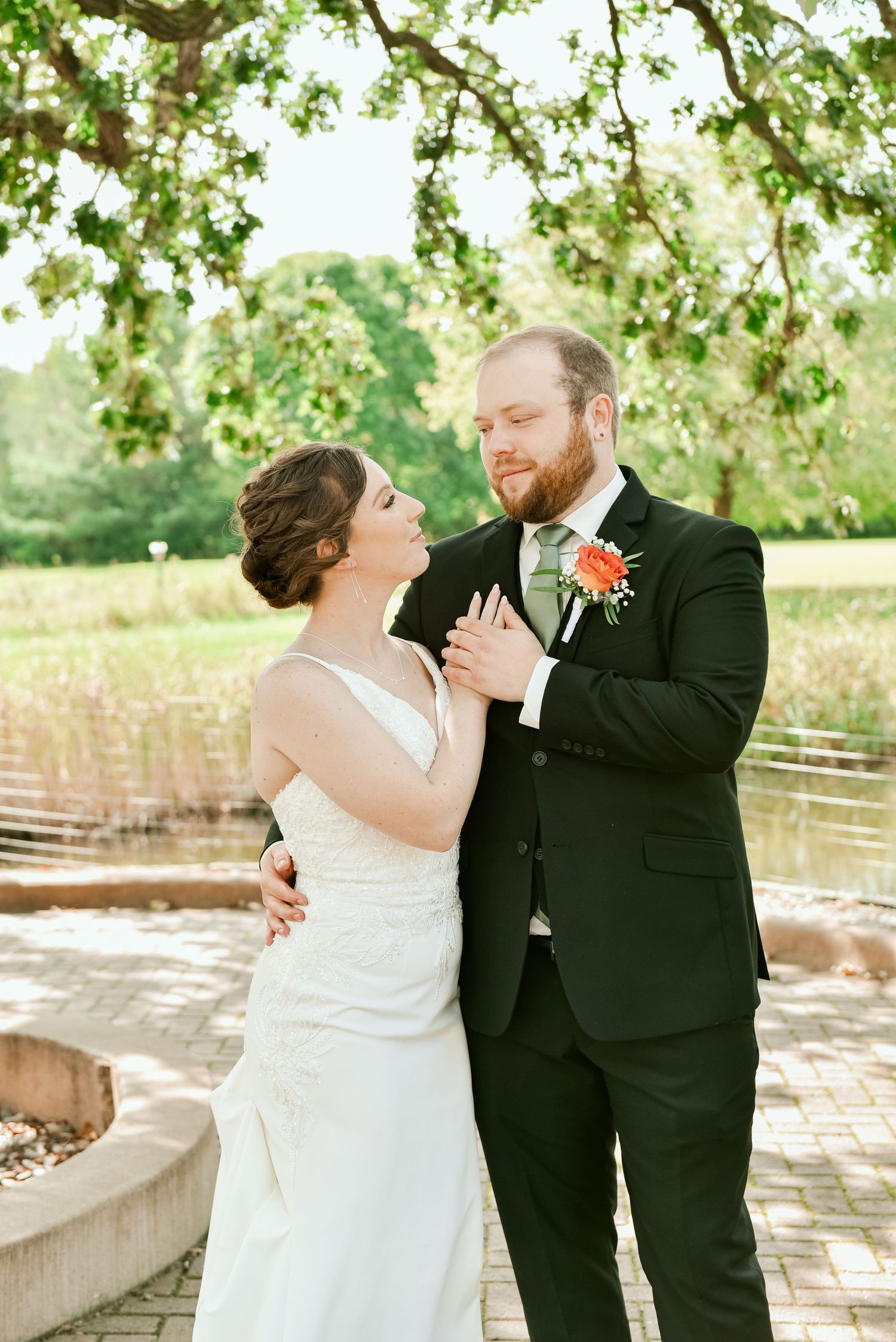 A romantic wedding couple shares an intimate moment under flowering tree branches on their special day.