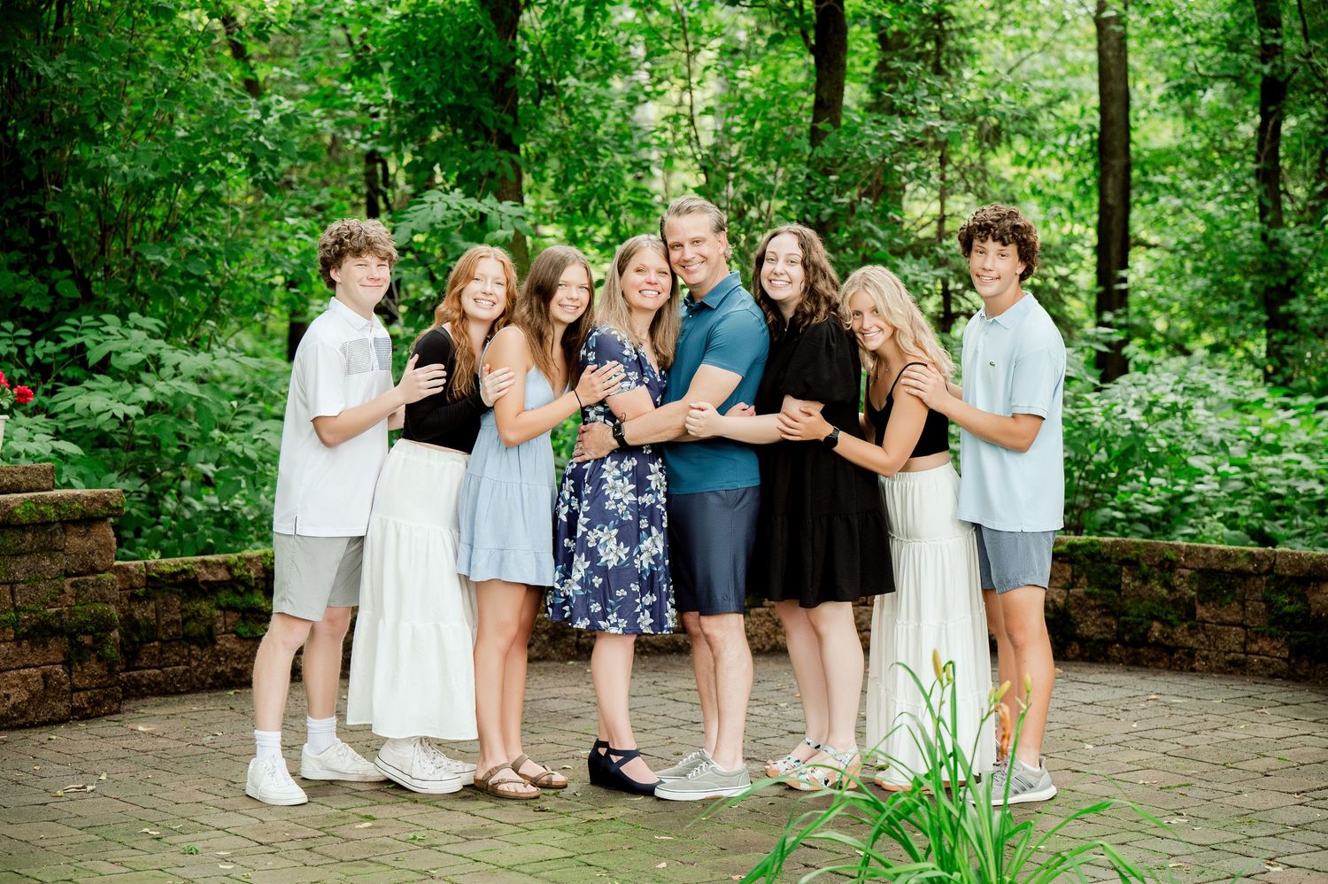 A cheerful group gathering outdoors on a stone patio surrounded by lush green forest scenery.