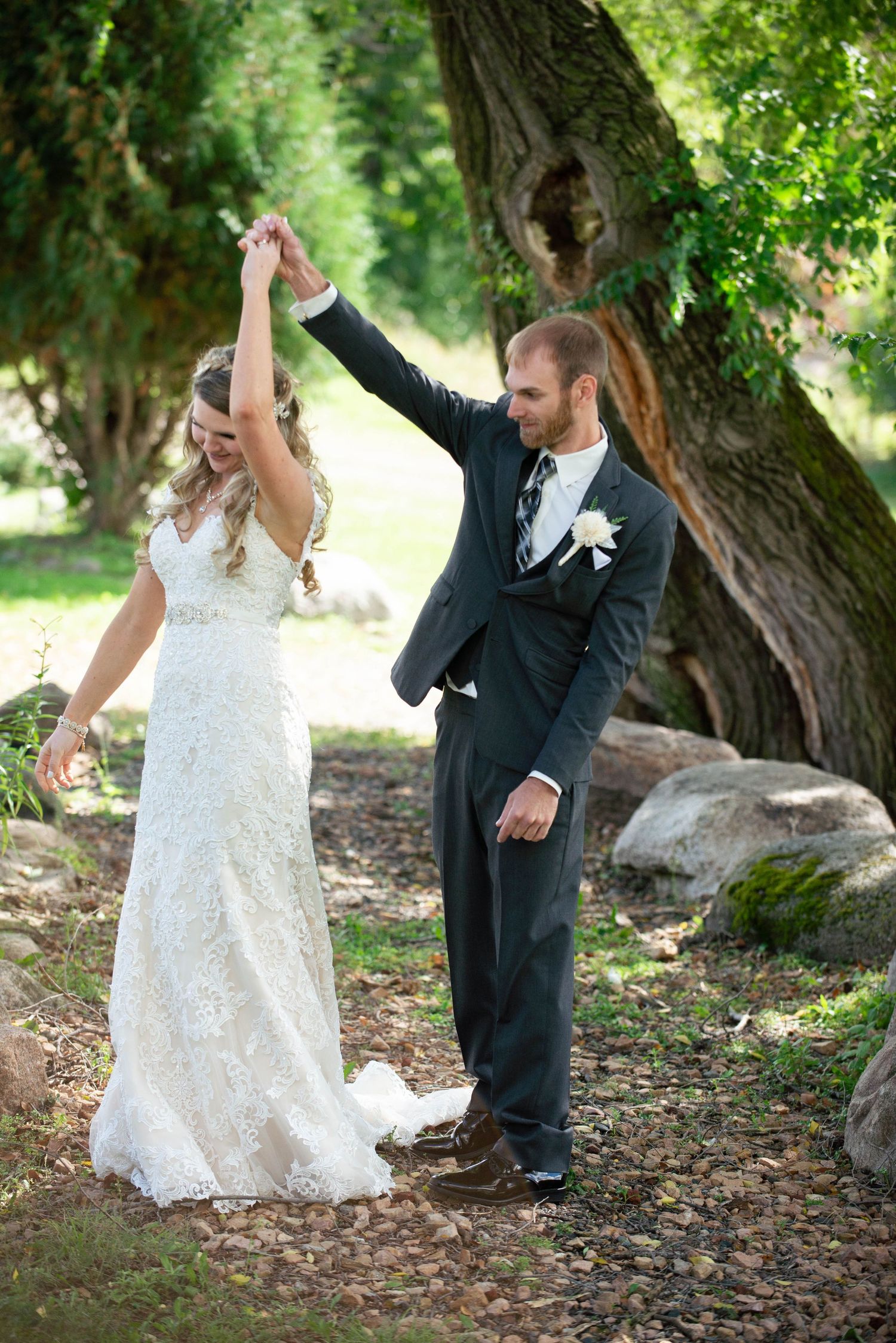 Wedding couple dancing outdoors near large tree with bride in lace gown and groom in dark suit. Rum River Barn Milaca Minnesota Weddings