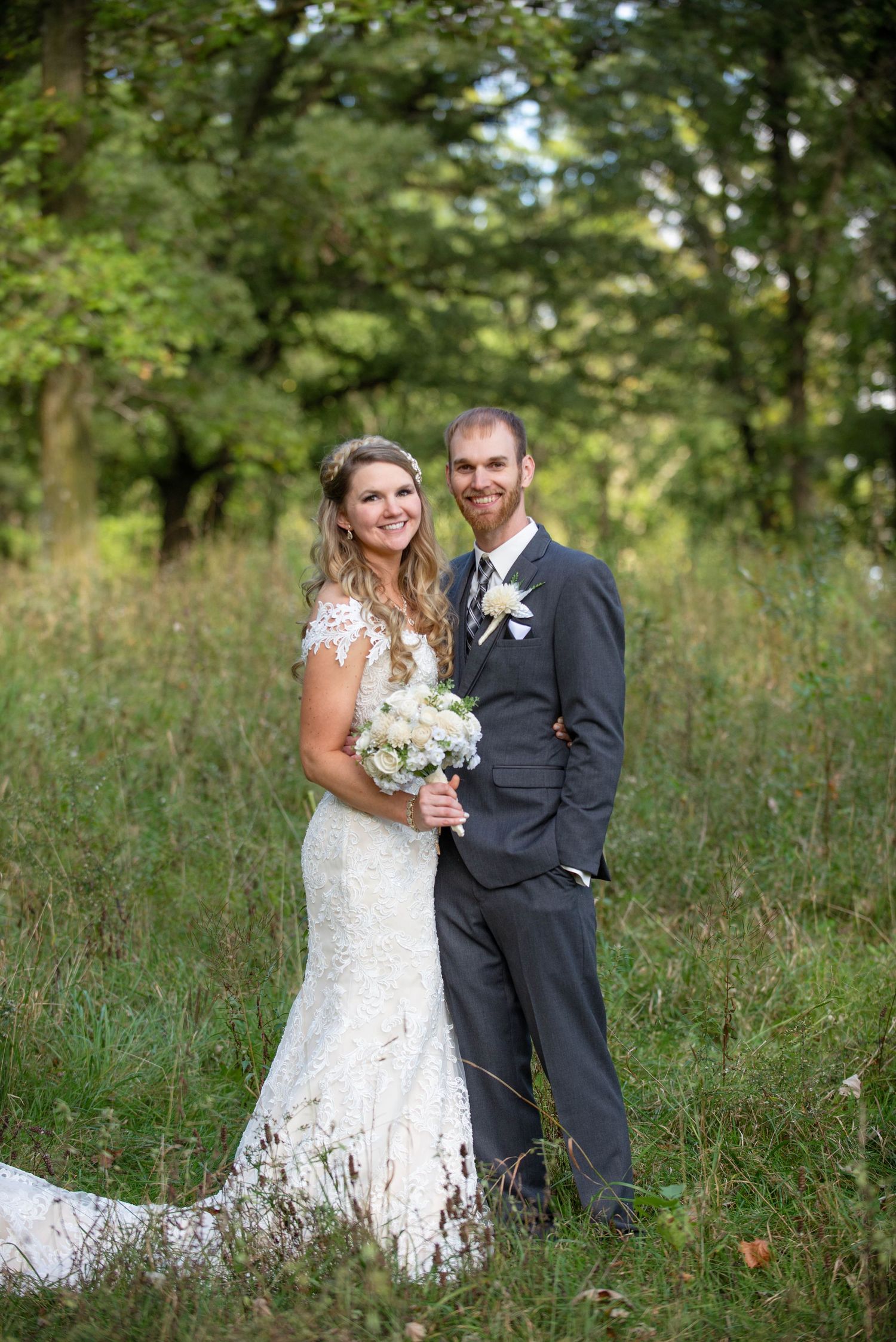 A newlywed couple poses together in a scenic woodland setting during their wedding photoshoot. Rum River Barn Milaca Minnesota Weddings