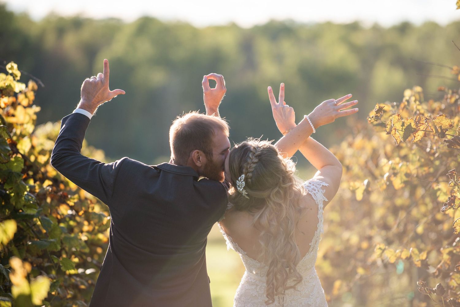 Newlyweds embrace in golden sunlight during sunset creating a romantic silhouette against the glowing sky. Rum River Barn Milaca Minnesota W