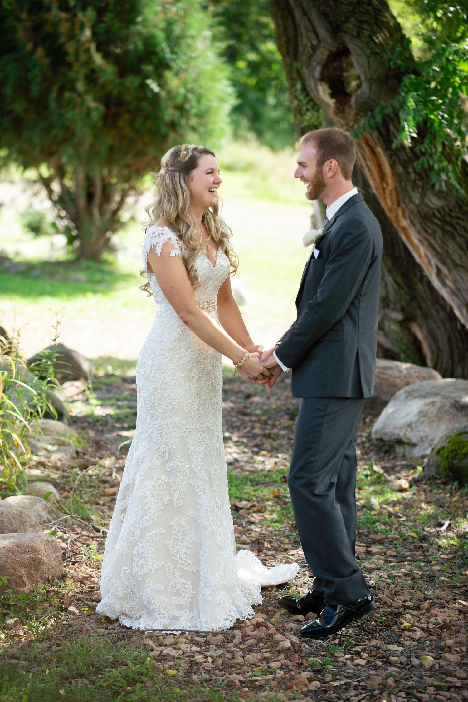 A romantic outdoor wedding scene with the couple holding hands under a rustic tree. Rum River Barn Milaca Minnesota Weddings