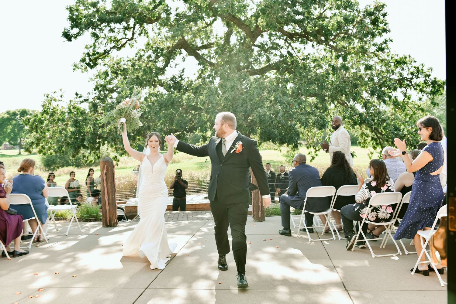 Newlyweds celebrate with joyful expressions during their outdoor wedding recession.