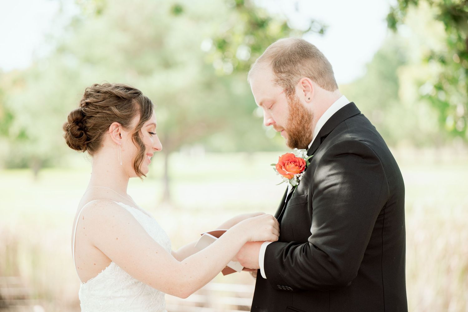 A romantic wedding couple shares an intimate moment while holding hands in an outdoor garden setting during a photo session.