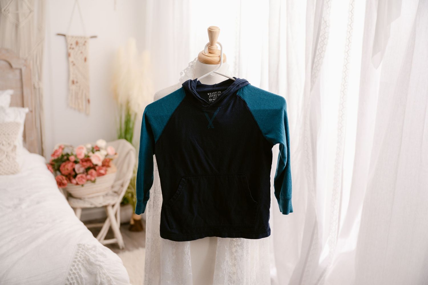 A black and teal raglan baseball style shirt displayed on a mannequin torso against a white curtain backdrop.