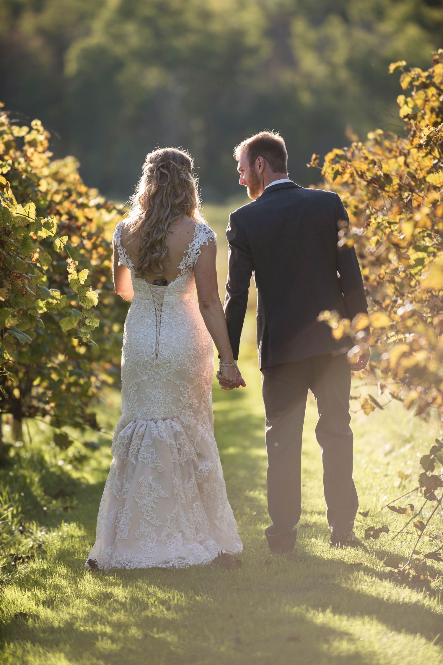 Sunset wedding portrait of a couple walking through golden sunlit foliage. Rum River Barn Milaca Minnesota Weddings
