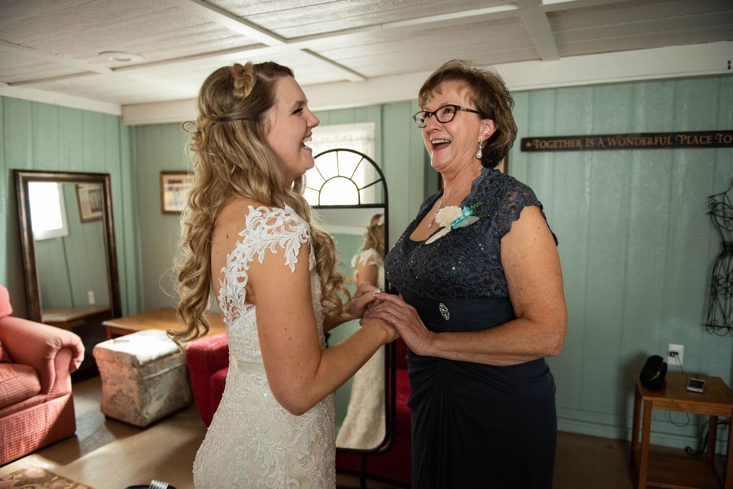 Wedding party members in turquoise dresses and cream-colored lace gown share emotional moments together. Rum River Barn Milaca Minnesota Wed