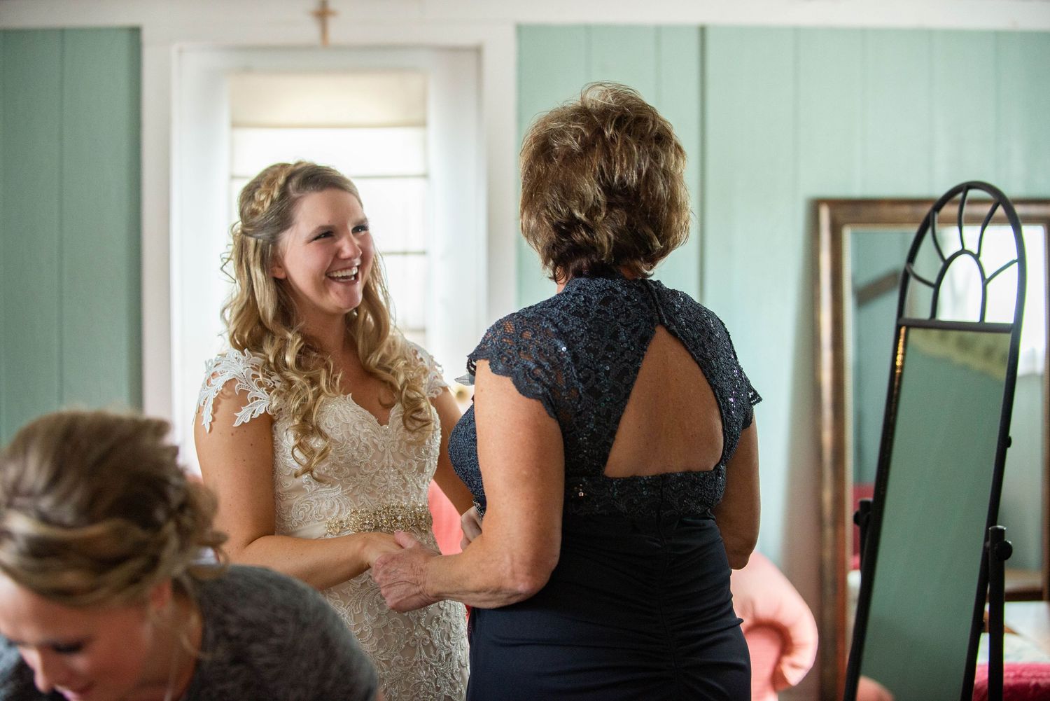 Getting ready scene with lace dress detail and preparation activity in mint green room. Rum River Barn Milaca Minnesota Weddings