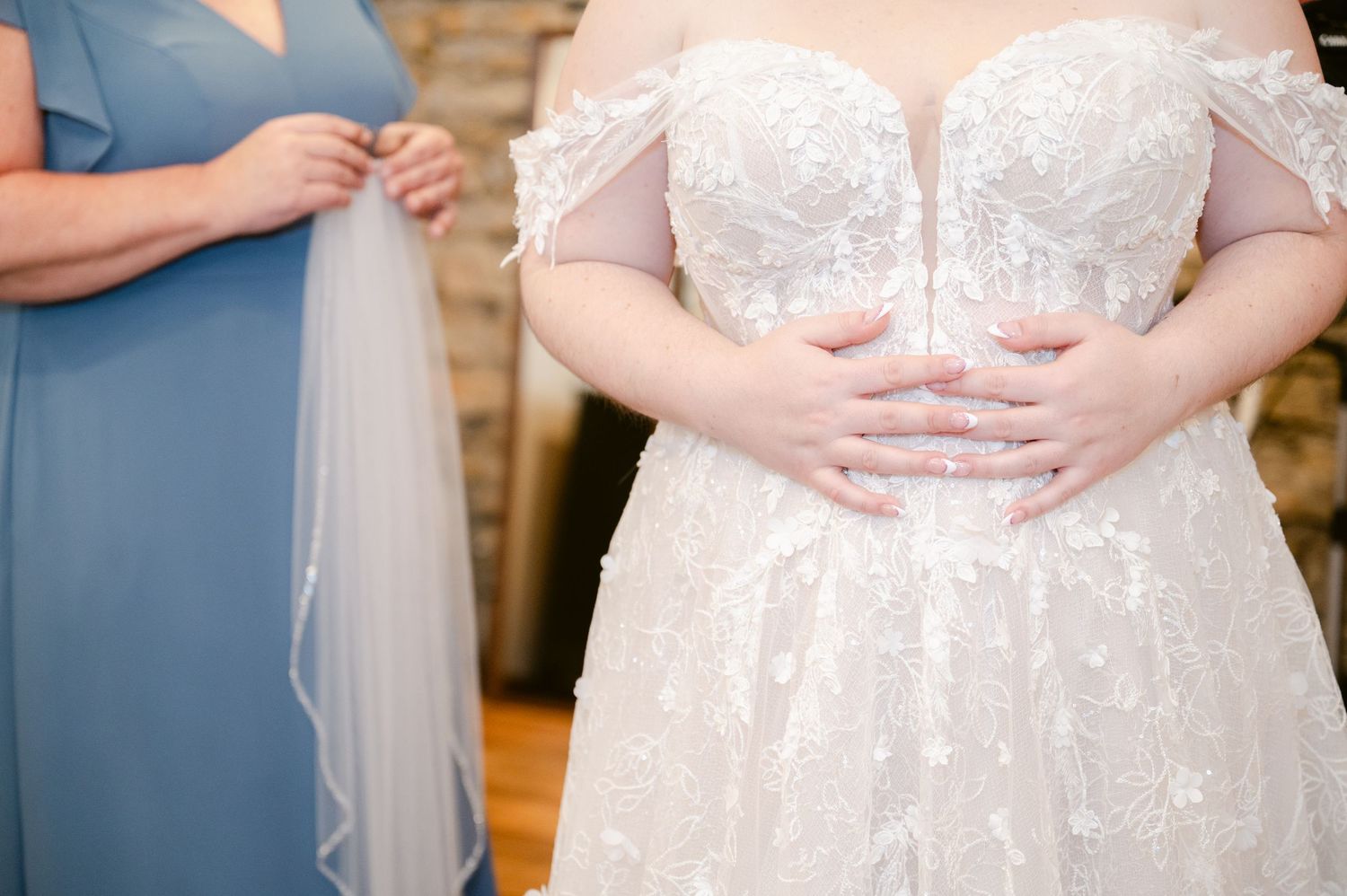 Close-up detail of an elegant white lace wedding dress bodice with delicate off-shoulder design.