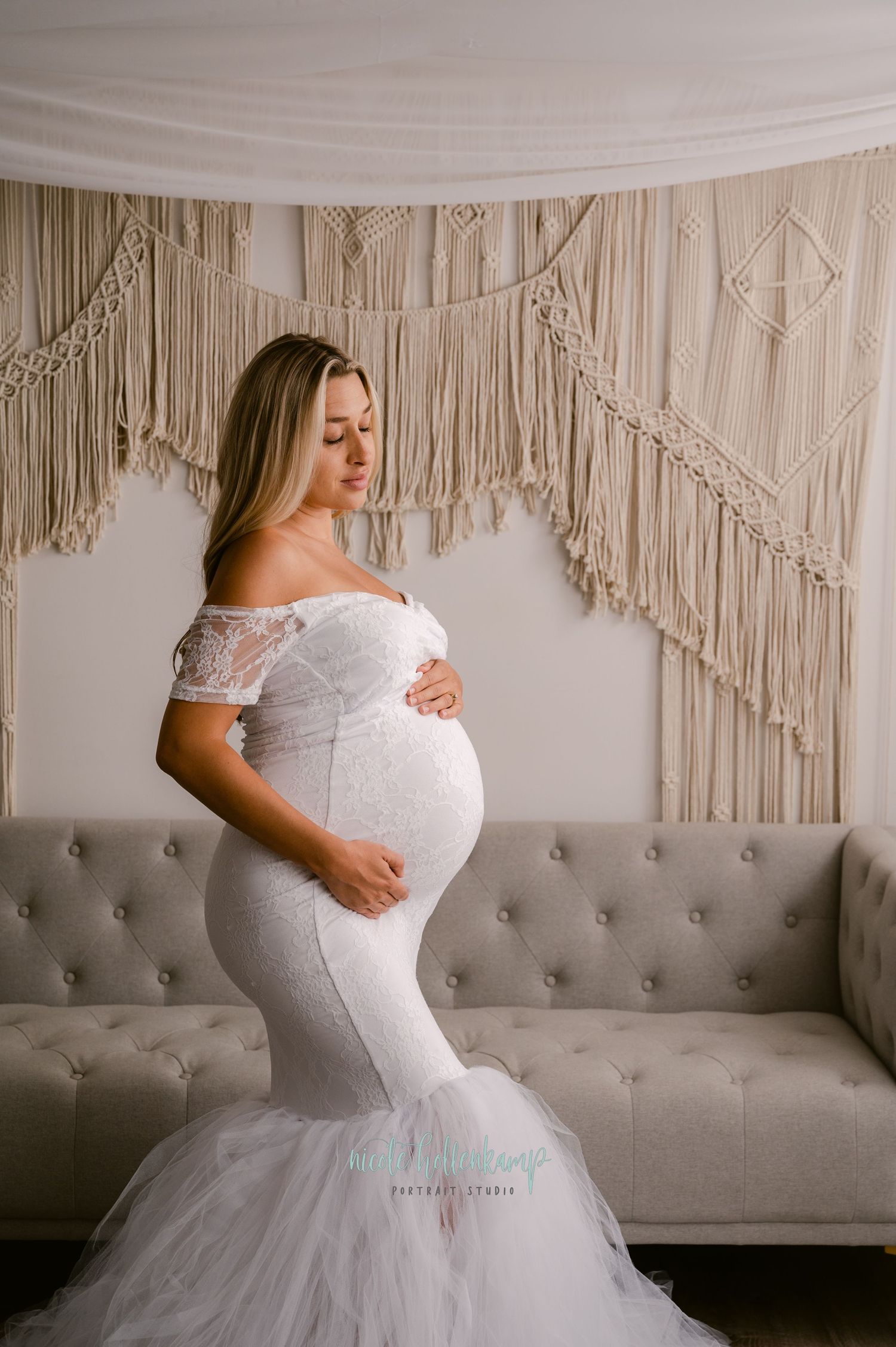 Beautiful maternity photo featuring an elegant white lace mermaid gown against a macrame wall backdrop.