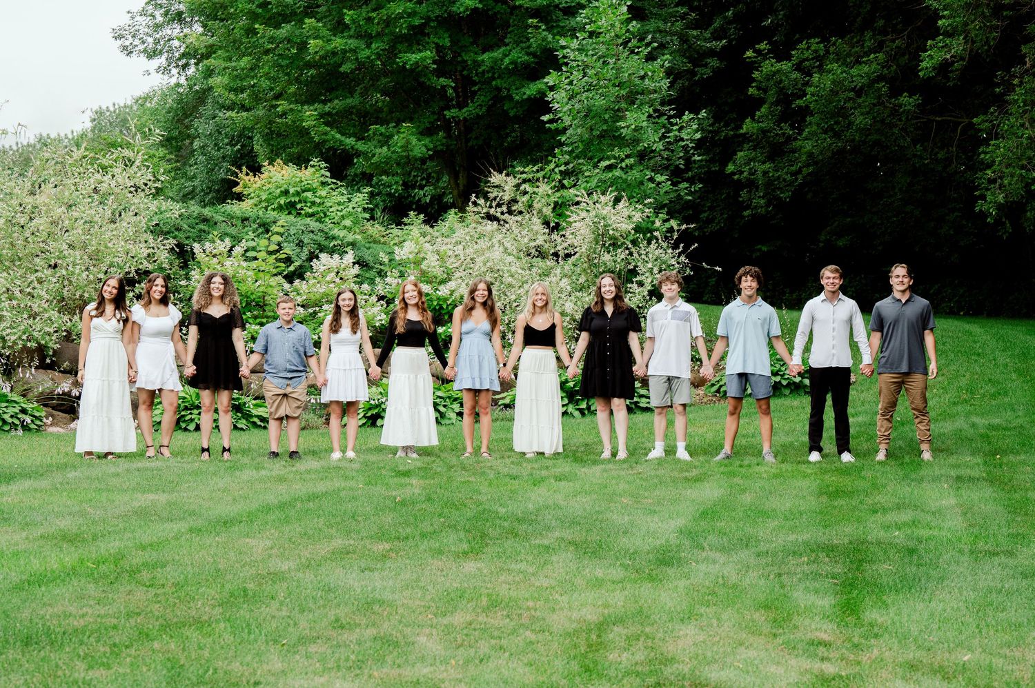 Clear Lake MN Family Photos: A group lined up on grass wearing coordinated outfits of white, black and grey for a group photo.
