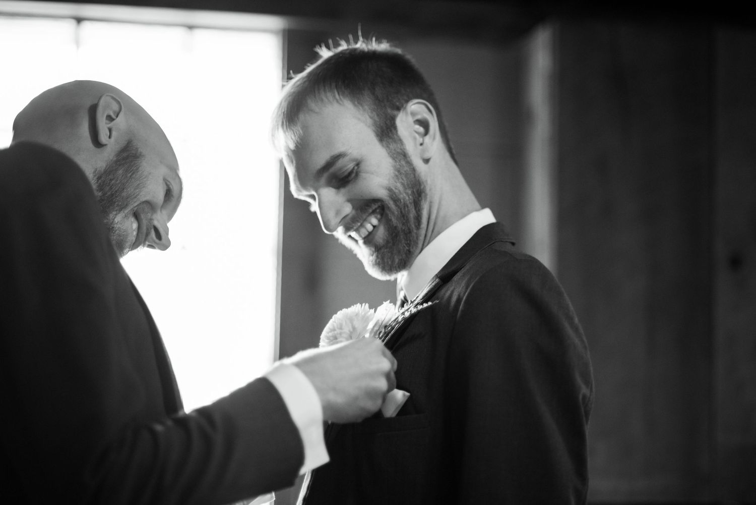 Black and white photo series showing different moments of groom and groomsmen preparing formal attire before wedding ceremony.