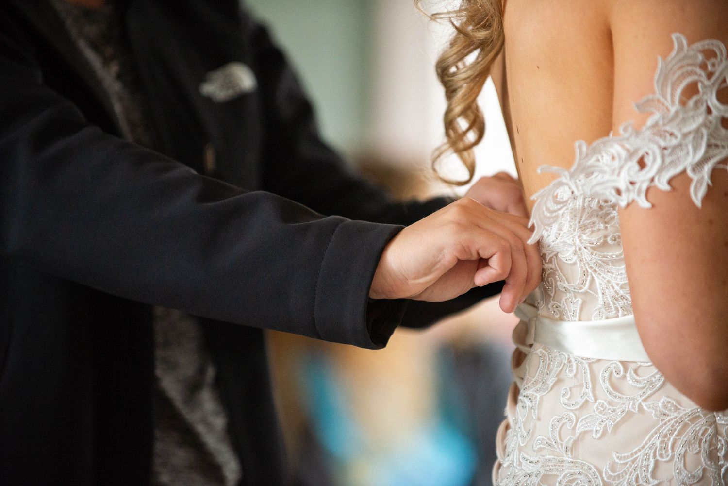 Close-up detail of lace wedding dress being adjusted. Rum River Barn Milaca Minnesota Weddings