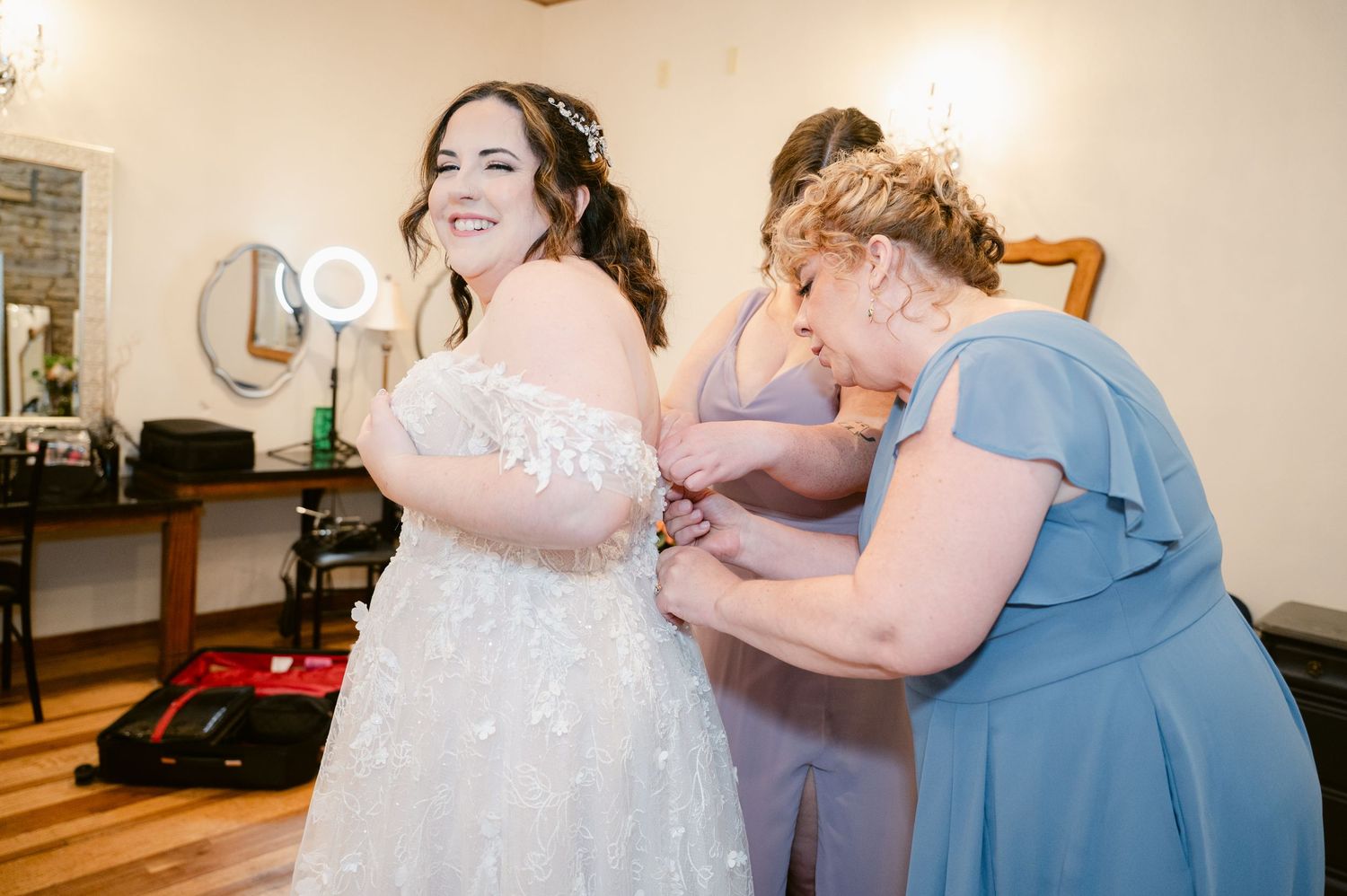 Someone helps adjust a white wedding dress in a bridal suite while getting ready for the ceremony.