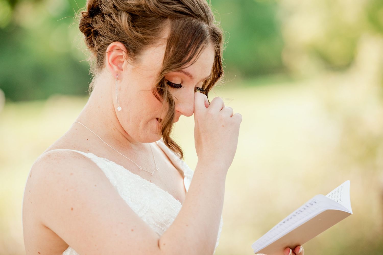 The Grands at Mulligans- Wedding Photos: A person adjusts their white wedding dress while gazing downward on a sunny outdoor day.