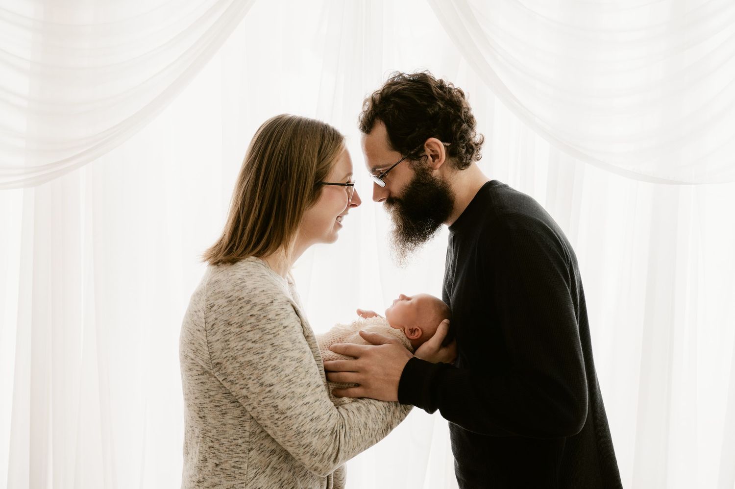 A romantic couple share an intimate moment while embracing in soft white light.