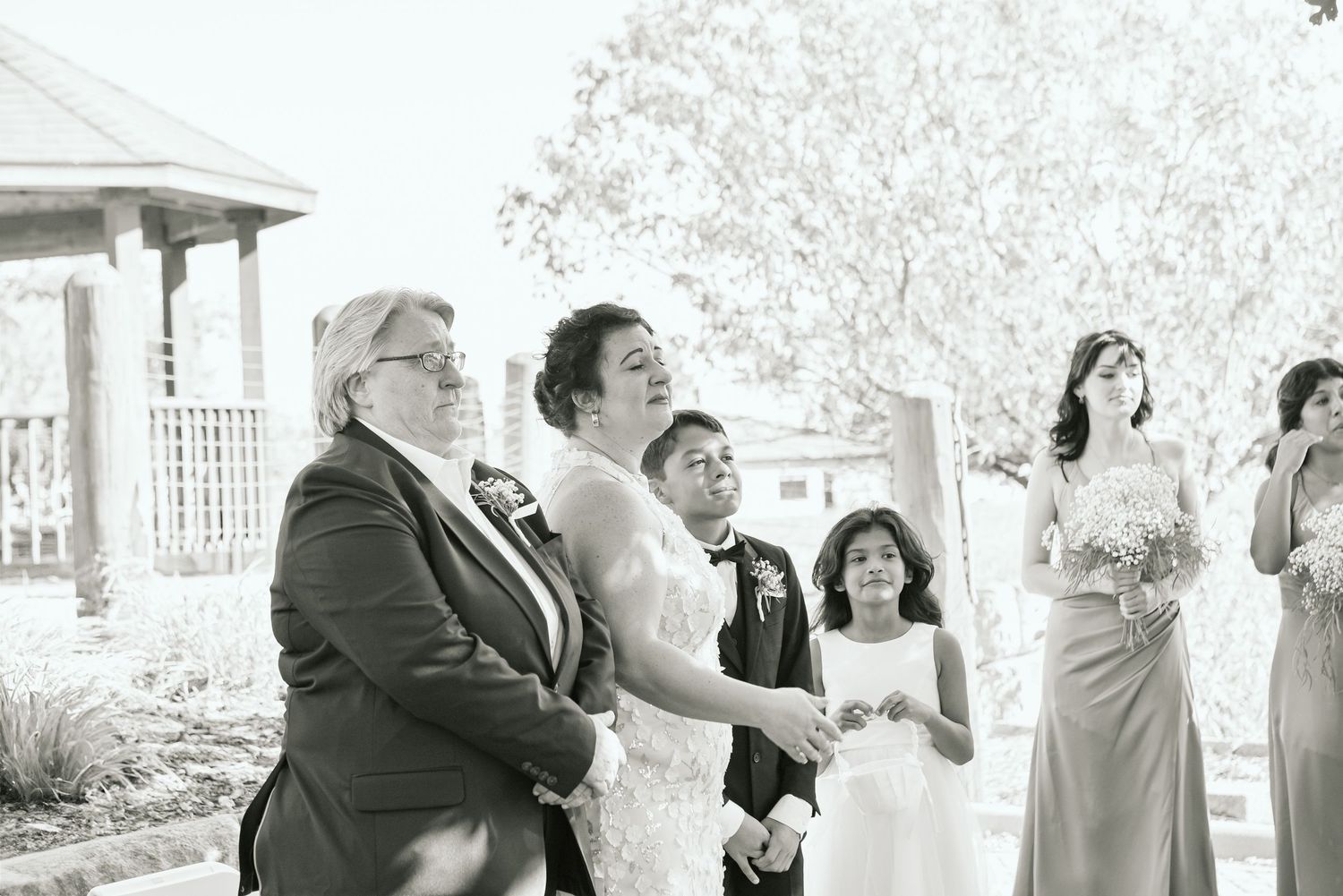 Black and white photos capture candid moments during an outdoor wedding ceremony.