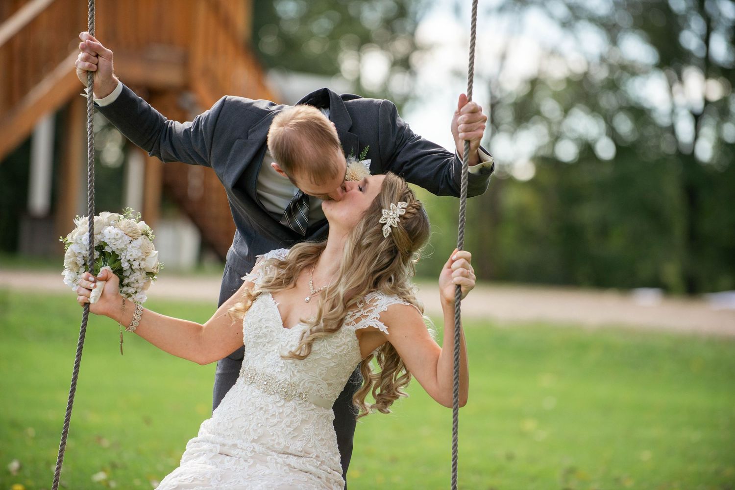 Creative wedding portrait of couple sharing romantic moment on outdoor swings. Rum River Barn Milaca Minnesota Weddings