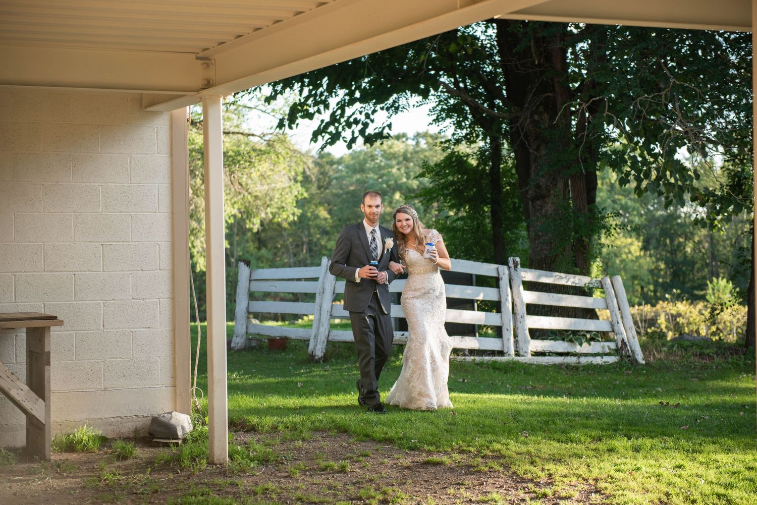 A couple shares a tender moment together on a rustic farm property with white fencing in the background. Rum River Barn Milaca Minnesota Wed