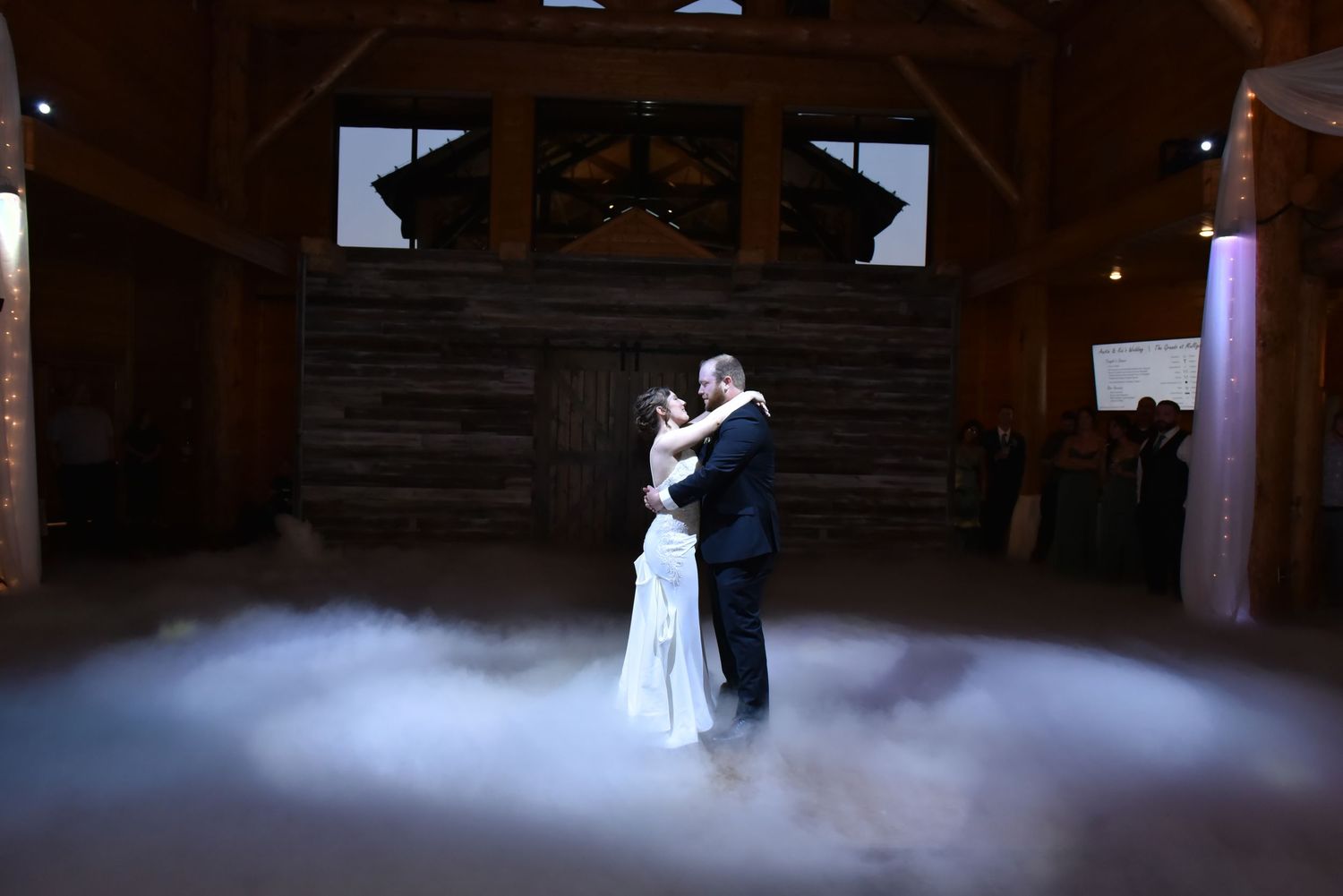 The Grands at Mulligans- Wedding Photos: A romantic first dance in a rustic barn venue with atmospheric fog effects.
