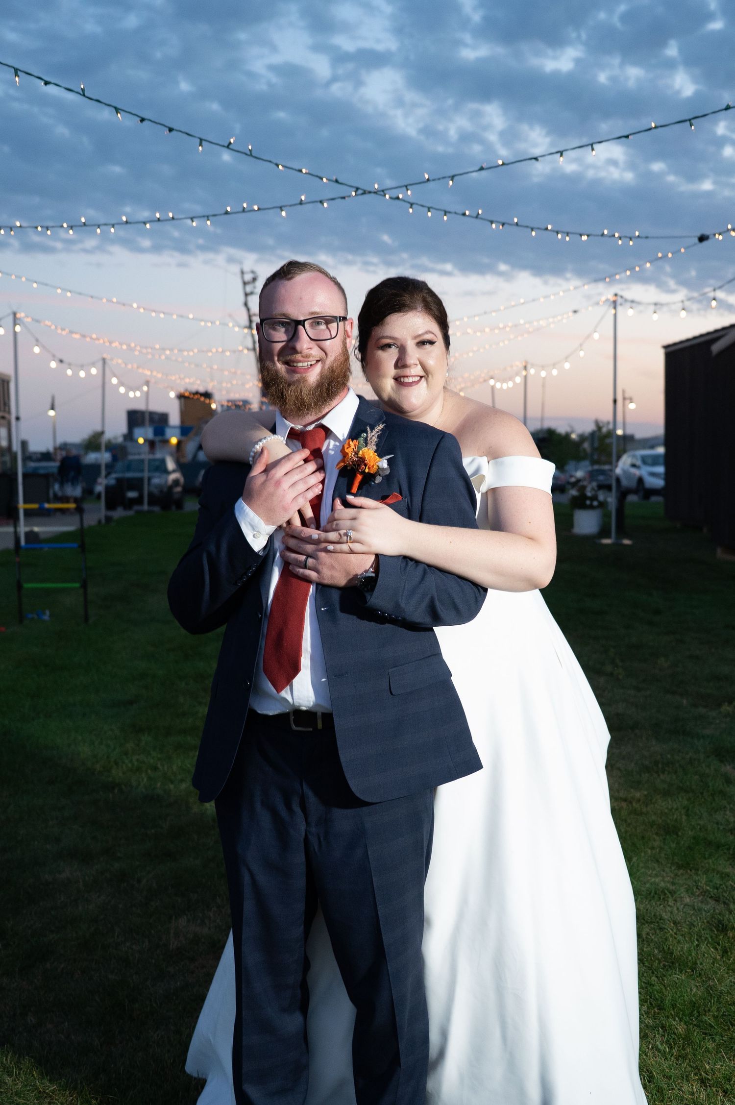 Pier B Duluth Wedding Newlyweds dance under string lights at sunset during outdoor reception celebration.