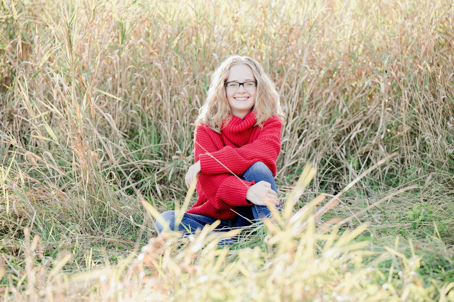 Senior Portrait in Foreston MN relaxing in golden field of tall grass during sunset photoshoot.