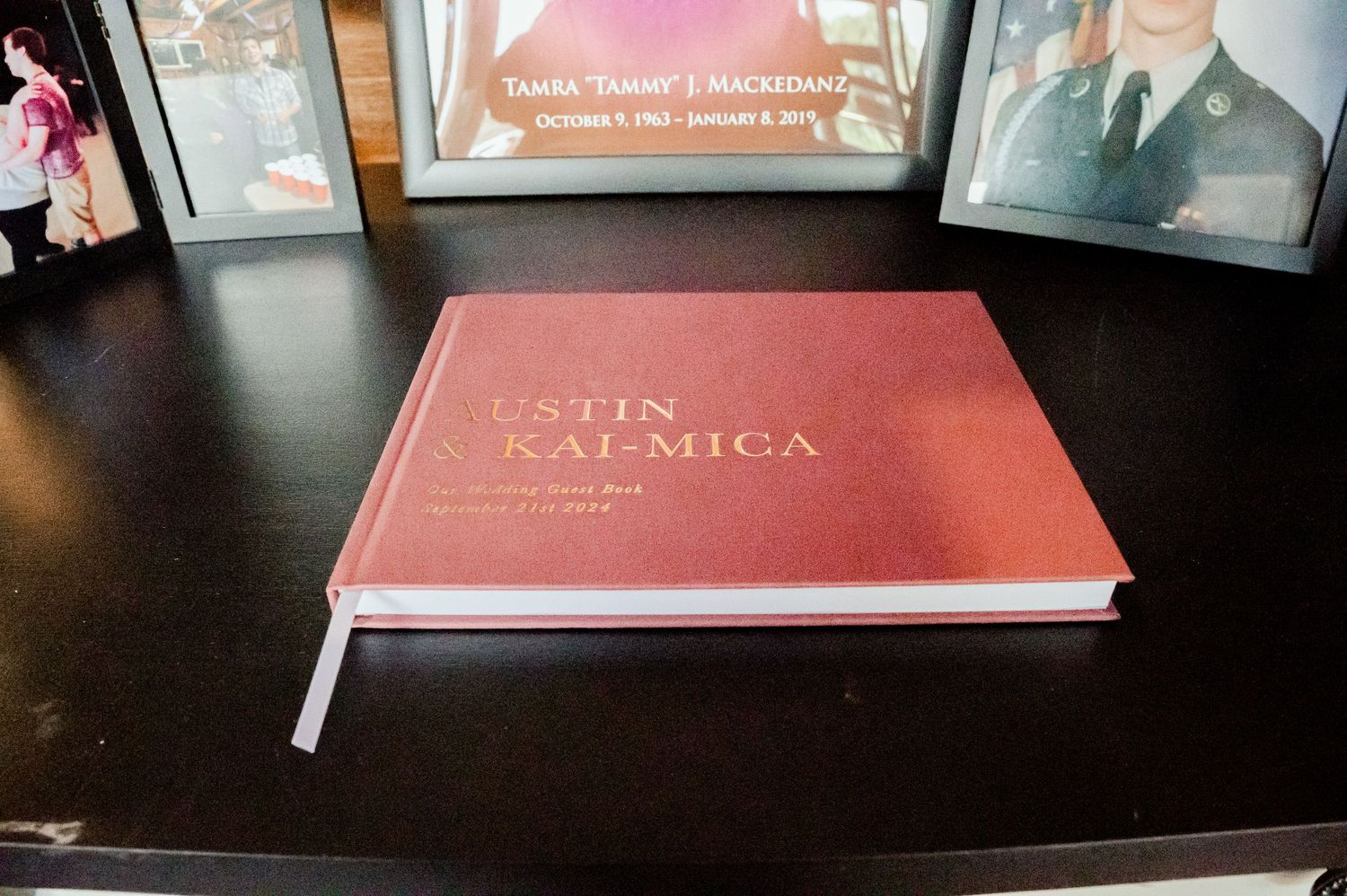 The Grands at Mulligans- Wedding Photos: A red hardcover photo album or book placed on a dark wooden surface.