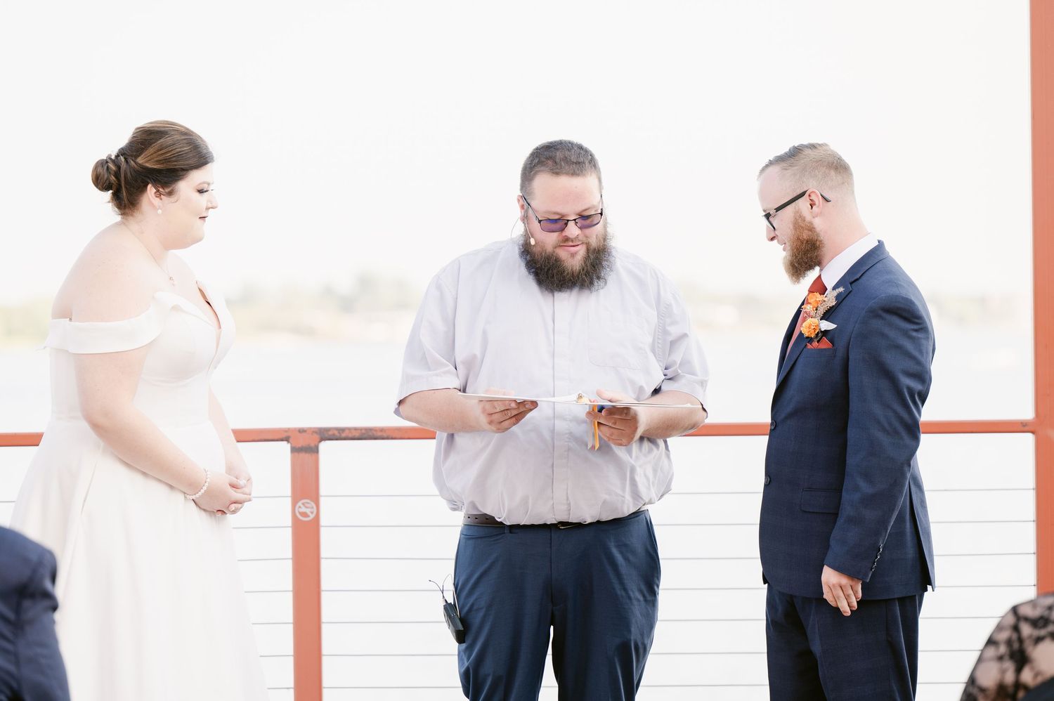 Pier B Duluth Wedding Two people in formal attire interact outdoors with reddish architecture elements visible in the background.
