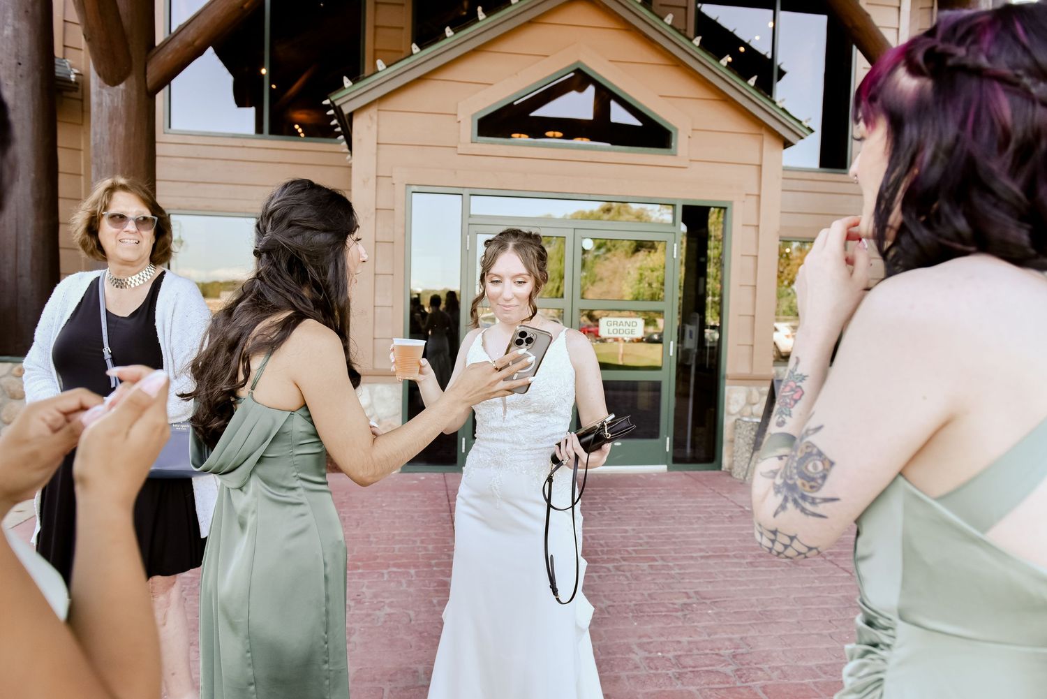 Wedding celebration on a sunny patio with guests in sage green dresses.