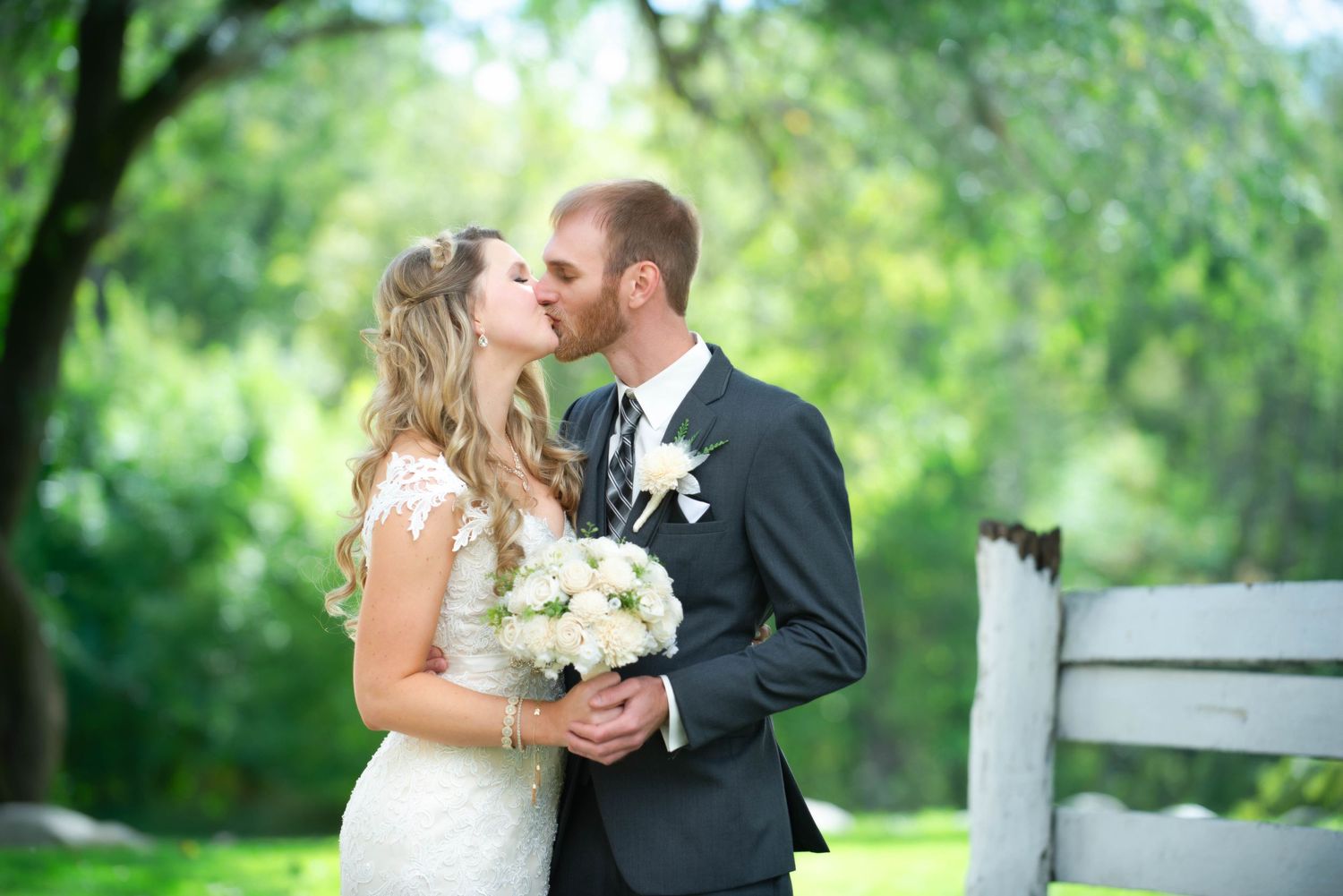 A romantic outdoor wedding photo session featuring a couple with a bouquet in a lush green setting. Rum River Barn Milaca Minnesota Weddings