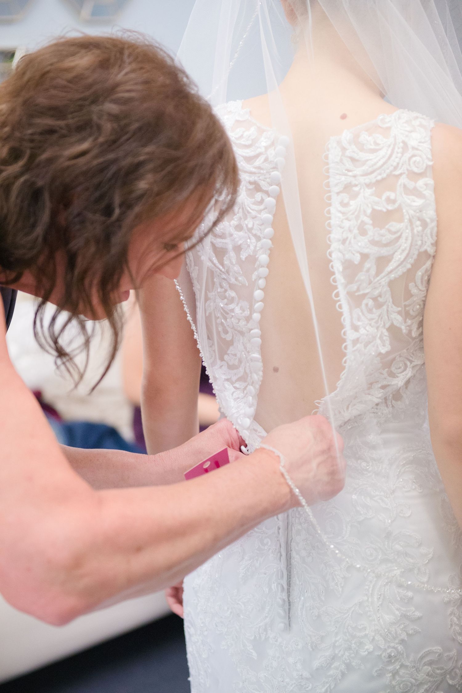 Close-up details of intricate lace buttons and embroidery on back of white wedding gown. Andover wedding at Magestic Oaks Golf Club