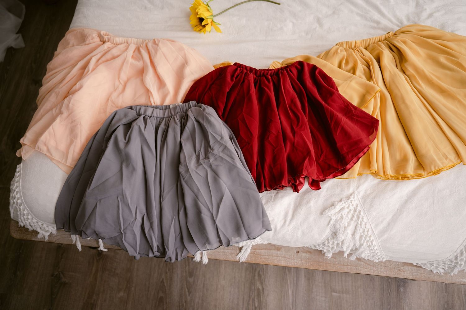 Four colorful velvet ballet dance skirts in gray, pink, burgundy, and yellow arranged on a white surface.
