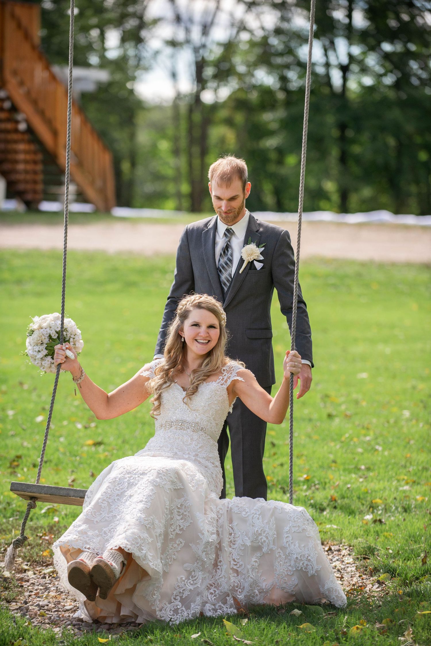 A playful wedding photo featuring the couple on a wooden swing in an outdoor setting. Rum River Barn Milaca Minnesota Weddings